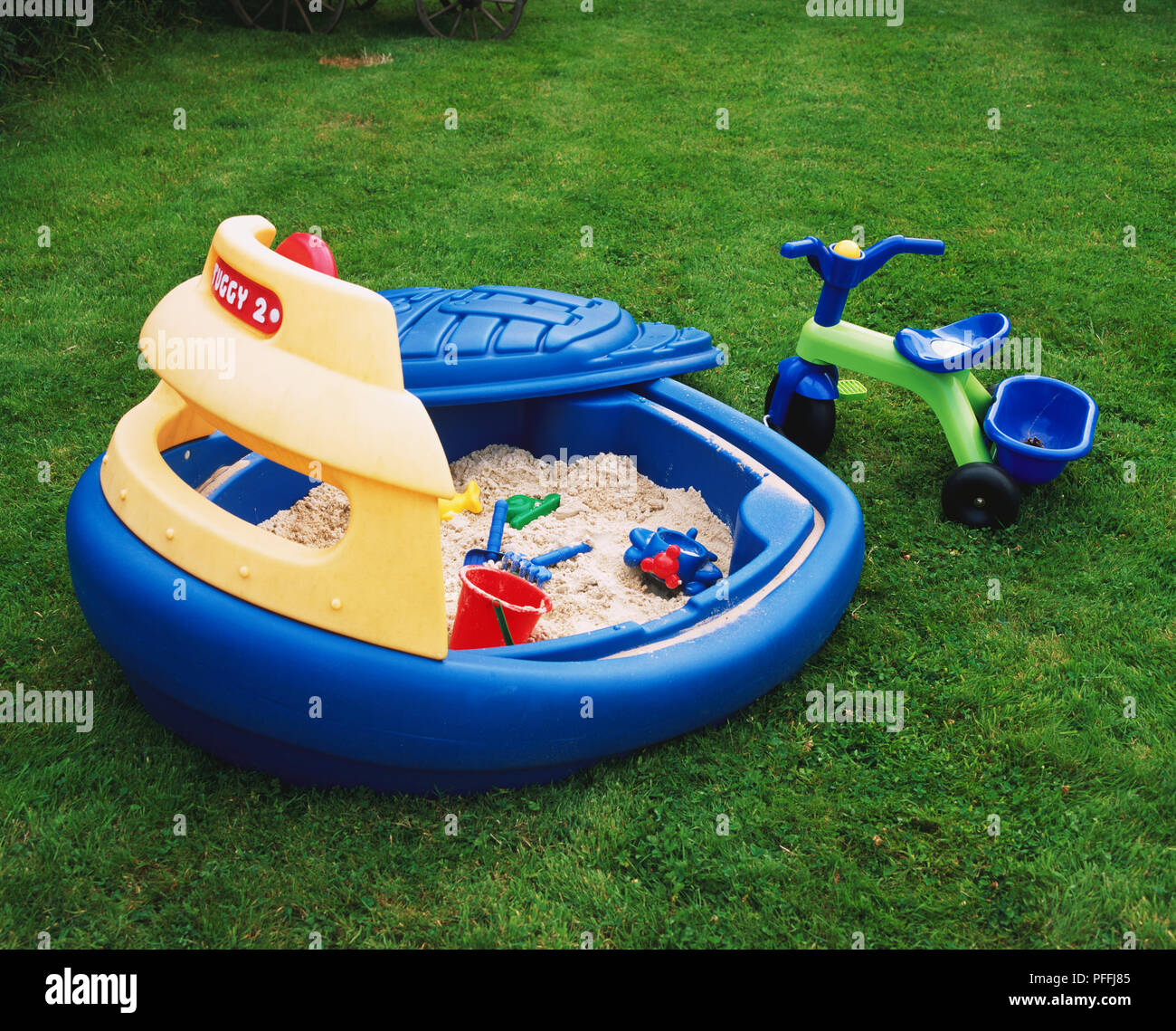 Kinder Kunststoff Sandkasten mit Deckel neben einem Dreirad Dreirad  Stockfotografie - Alamy