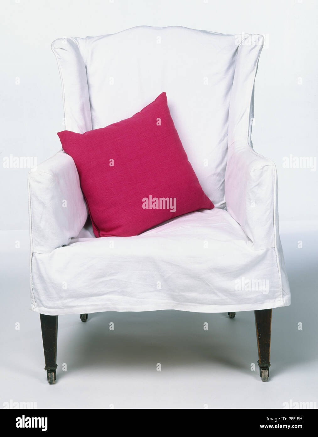 Junk-Sessel mit weißer Baumwolle lose Abdeckung und rosa Kissen, Vorderansicht. Stockfoto