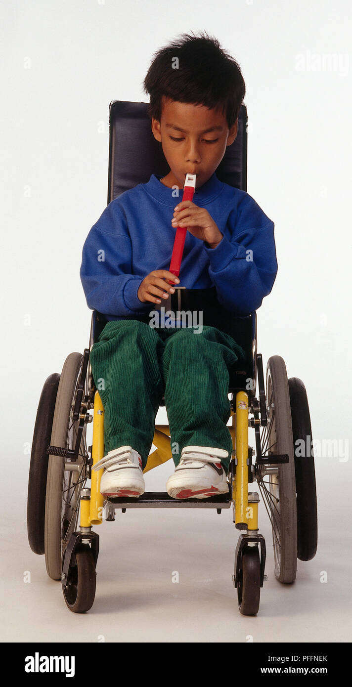 Vorderansicht des Jungen im Rollstuhl spielen Rot Pfeifen Stockfoto