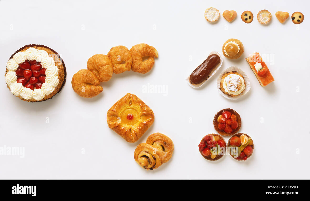 Auswahl an Kuchen und Gebäck, einschließlich Erdbeer Sahne Kuchen, Croissants, Dänisch, Obst Törtchen, Chocolate Eclair, Muffins, Ansicht von oben Stockfoto