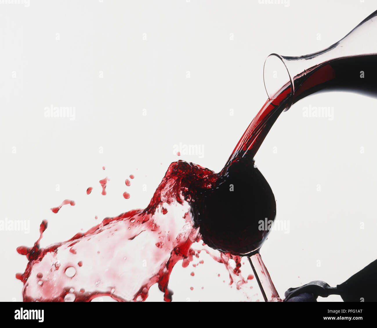 Splash durch Rotwein von Kolben in überquellenden Wein Glas geschüttet wurde erstellt, Seitenansicht. Stockfoto