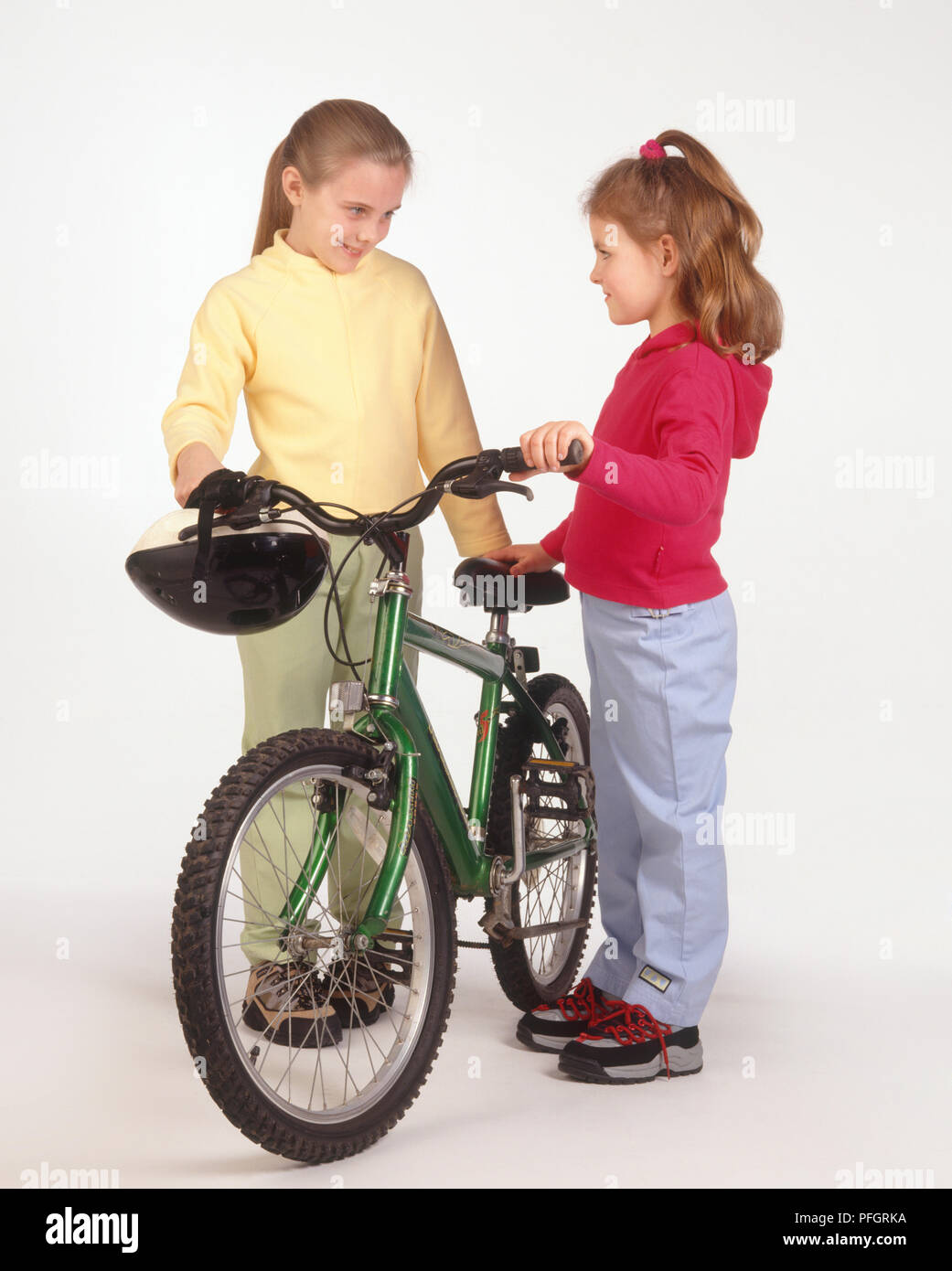 Zwei Mädchen stehen von Angesicht zu Angesicht, holding Mountainbike zwischen ihnen Stockfoto