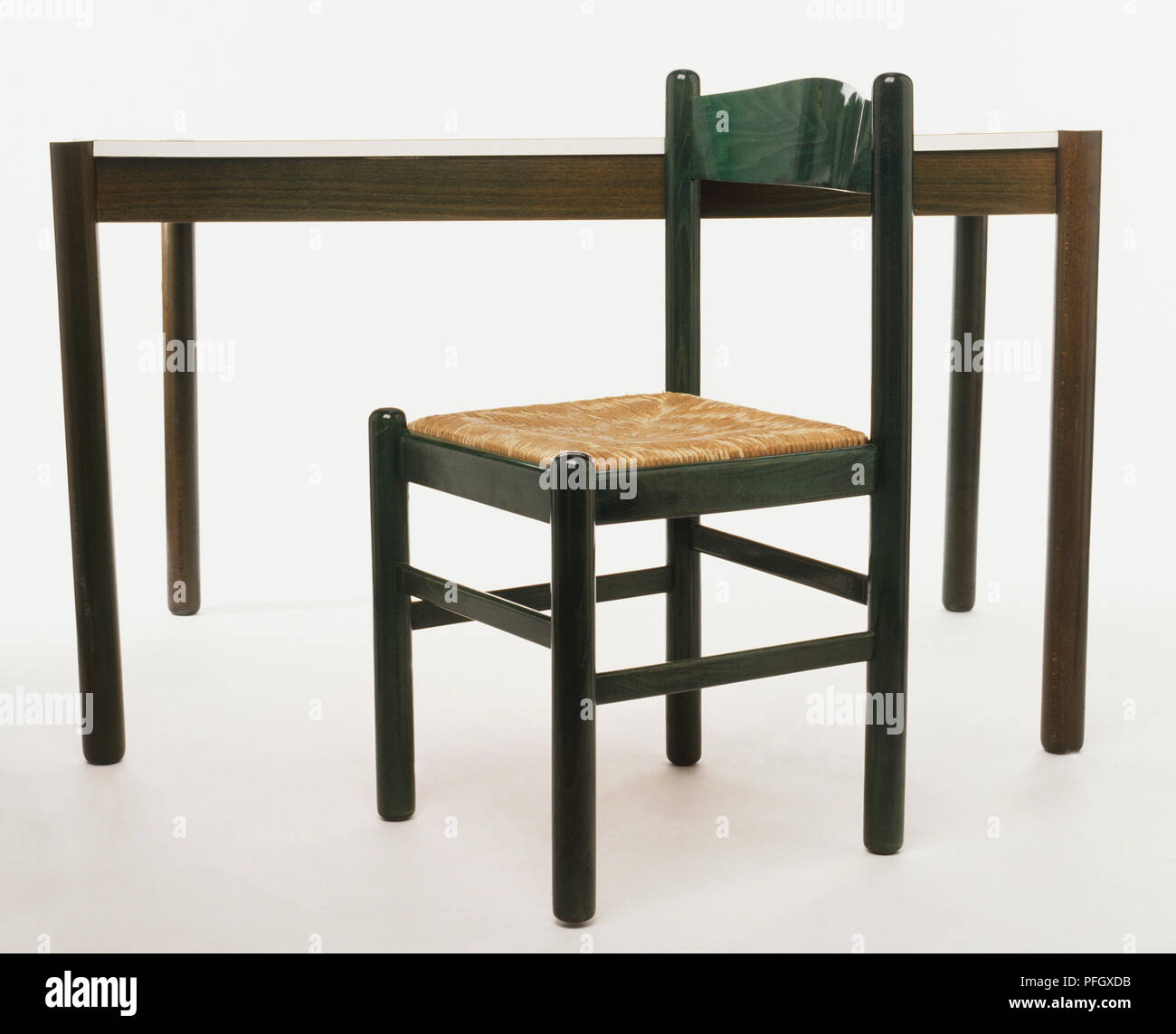 Ein grüner Stuhl mit einem Strohhalm Sitz vor einem Tisch Stockfoto