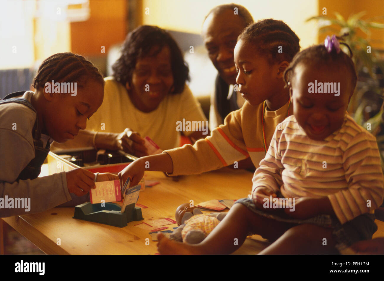 Familie um einen Tisch spielen ein Spiel Stockfoto