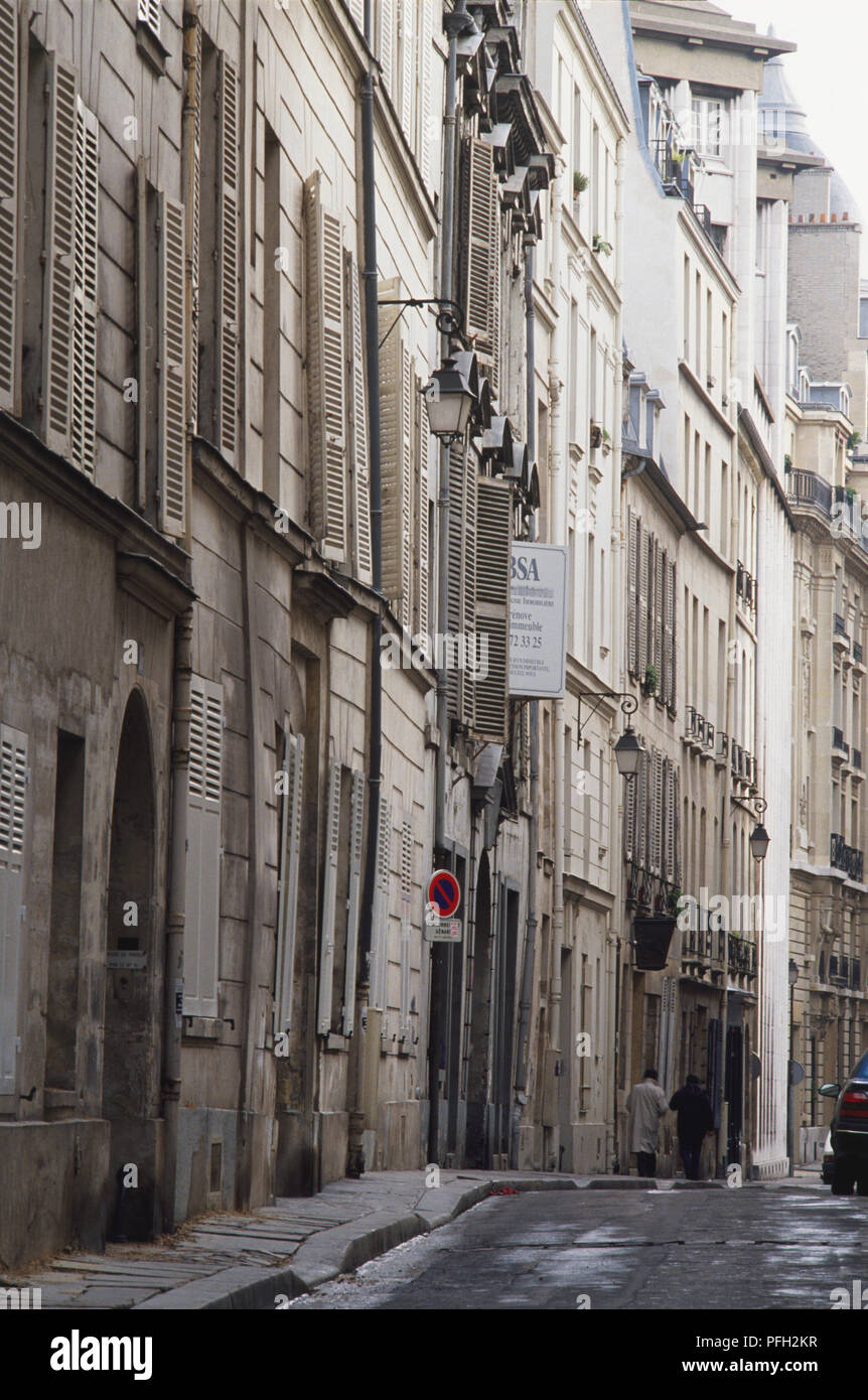 Frankreich, Paris, Marais, Gasse mit hohen Gebäuden gesäumt, zwei Menschen zu Fuß in der Ferne. Stockfoto