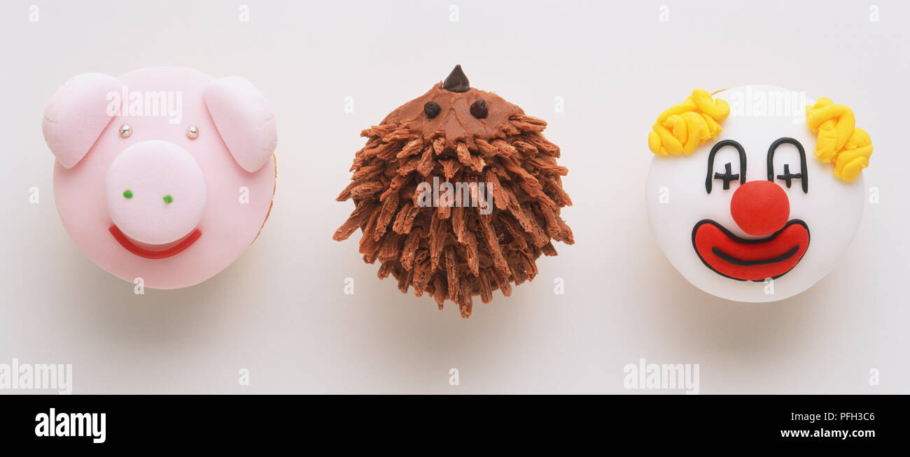 Drei Cupcakes mit dem Gesicht von einem Schwein eingerichtet, ein Clown und ein Igel, Ansicht von oben Stockfoto