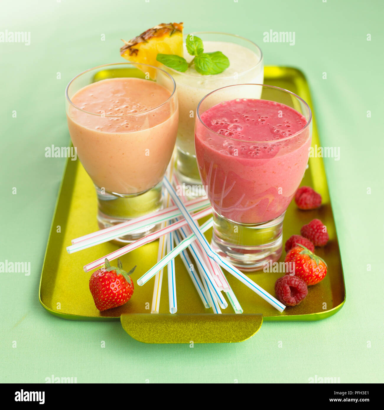 Smoothies, Trinkhalme und frische Früchte auf einem goldenen Tablett Stockfoto