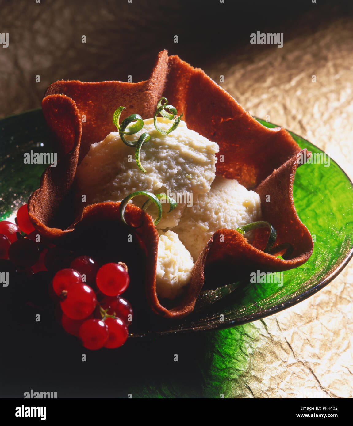 Gebackene Schokolade Warenkorb mit weißer Mousse gefüllt, garniert mit roten Johannisbeeren und Limettenschale, hohe Betrachtungswinkel Stockfoto