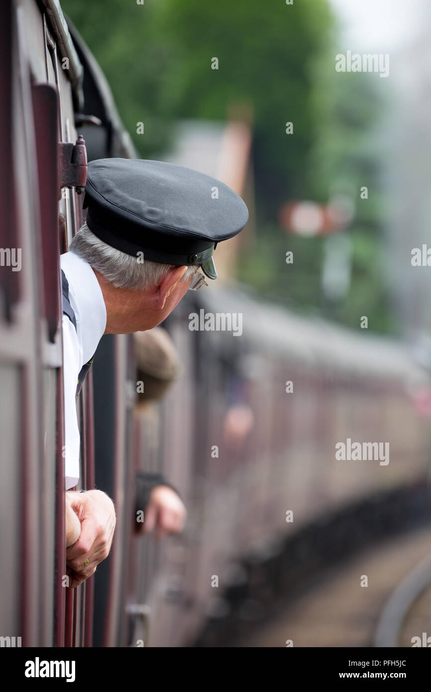 Ansicht der Rückseite des Ticket inspector (schirmmütze) lehnte sich aus Vintage Beförderung Fenster als Zug nähert. Reisen an Bord genommen. Stockfoto