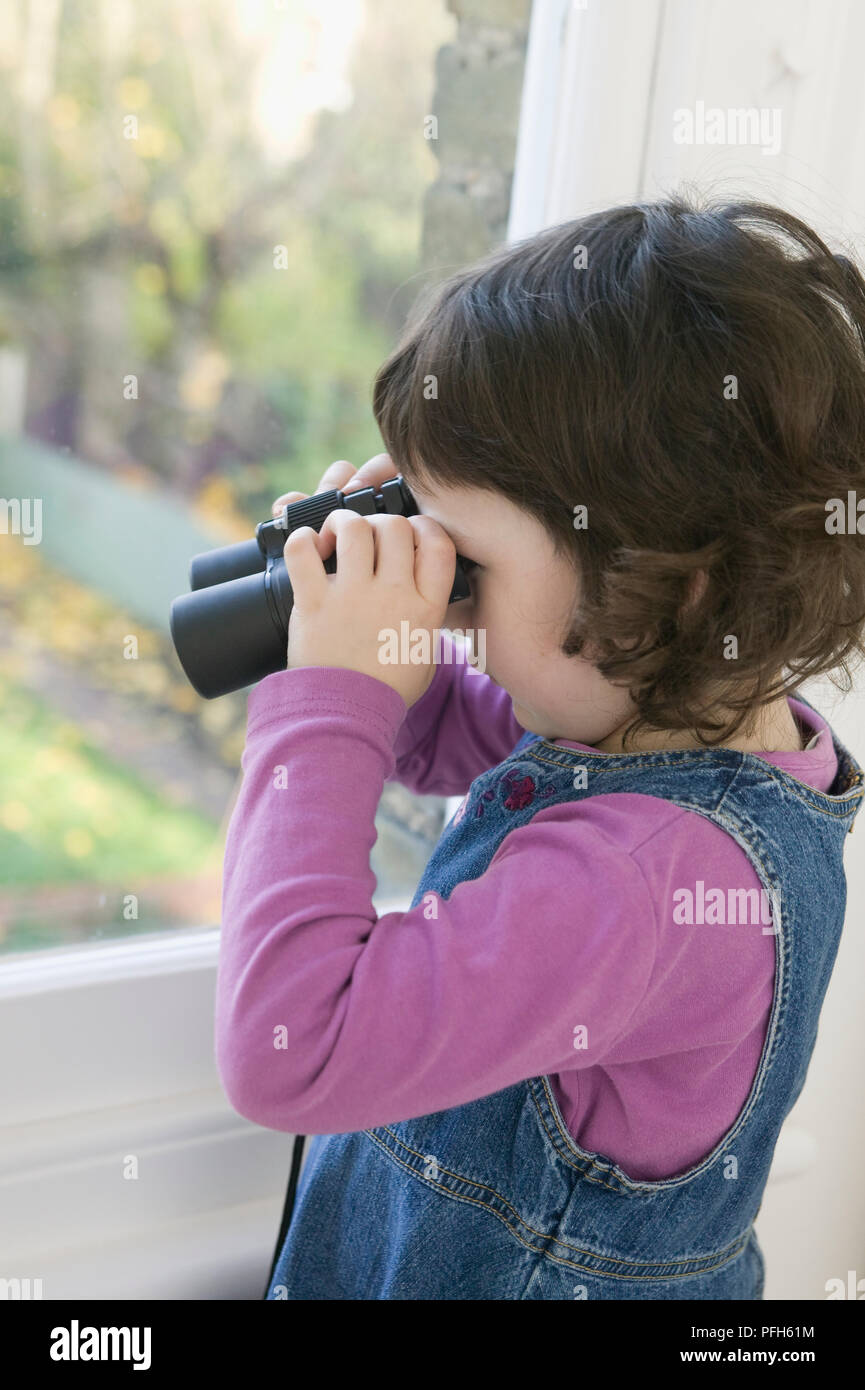 Stehendes Mädchen durch die Fenster schauen durch ein Fernglas Stockfoto