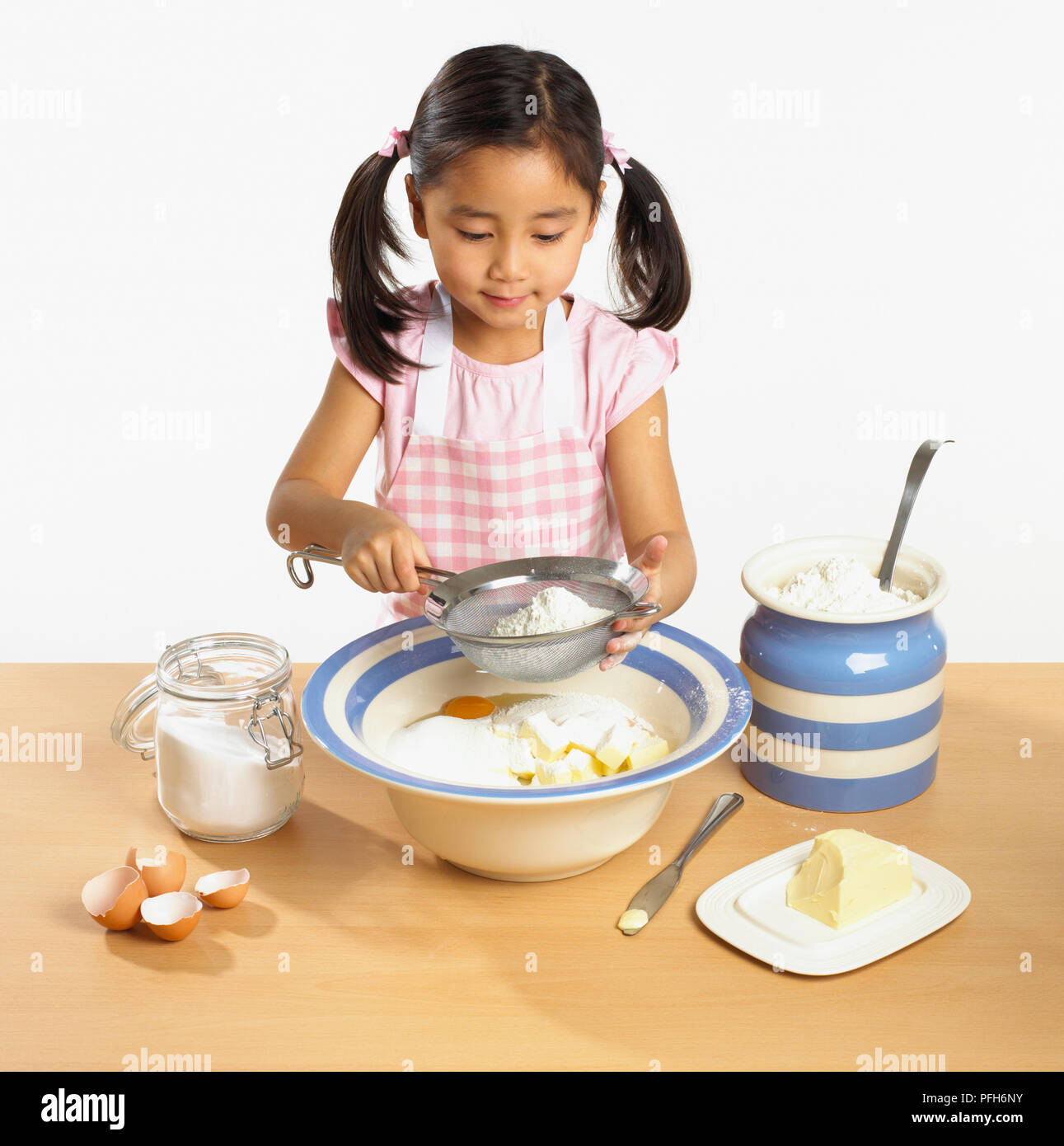 Mädchen sieben Mehl in Schüssel Butter, Eier und Zucker Stockfoto