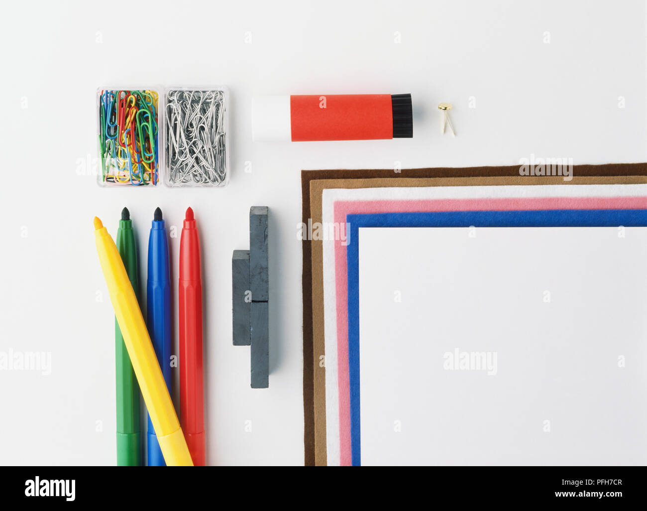 Zwei schachteln Büroklammern, Klebestift, Filzstiften, Holzkohle und Stapel von weißen und farbigen Papier Stockfoto