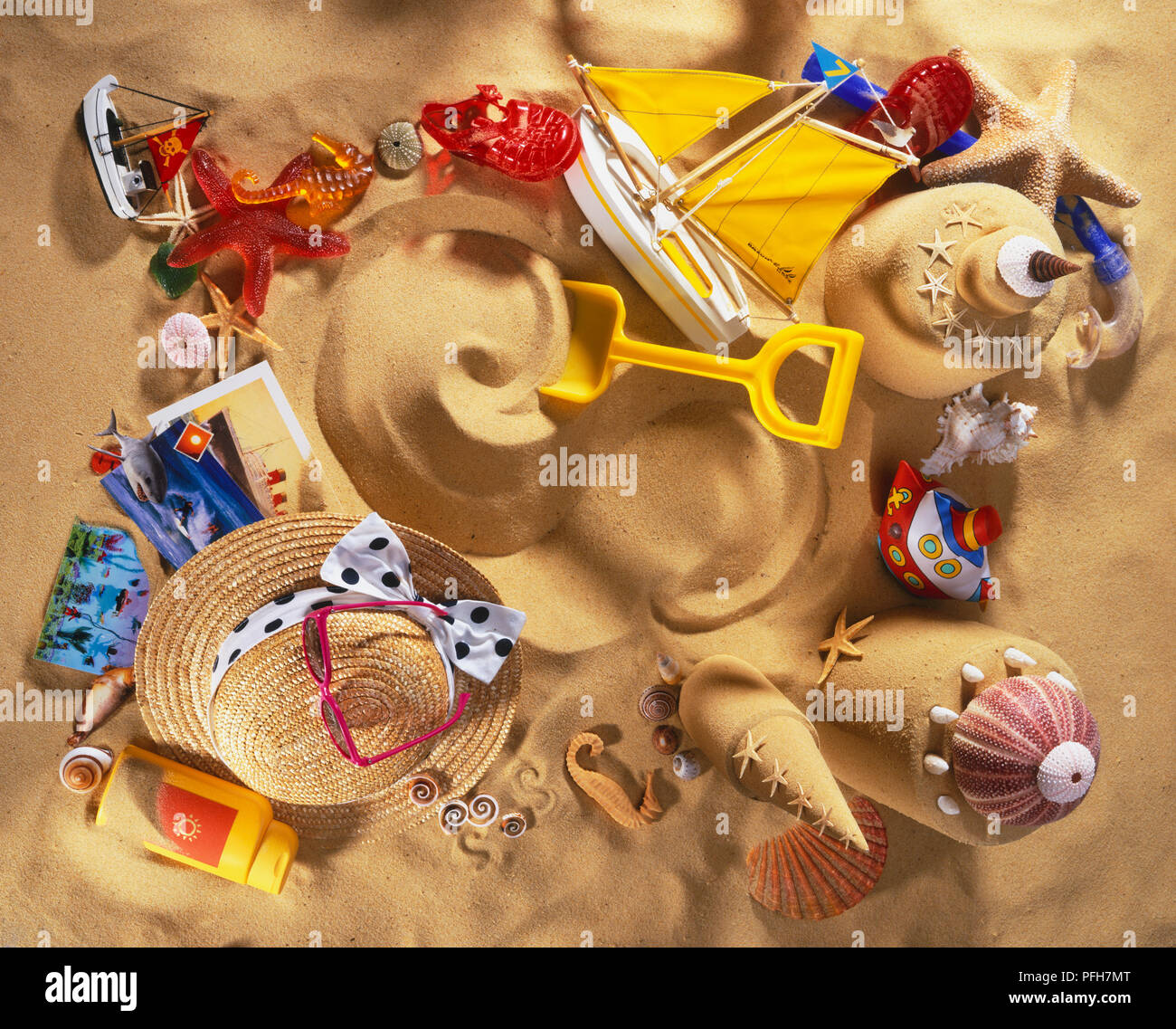 Sandburgen, Spielzeug, Strohhut und Sonnencreme in Sand, Ansicht von oben Stockfoto