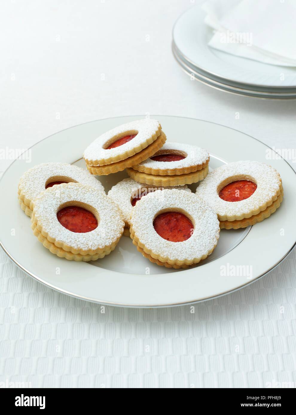 Spitzbuben, traditionell Deutsch, runde Kekse mit himbeermarmelade im Zentrum, serviert auf einem Teller, mehr Platten und Serviette in der Nähe, close-up Stockfoto