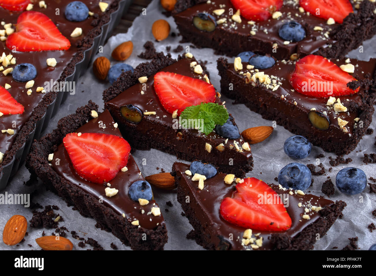 Köstlich süßen Keine backen Schokoladentorte mit Ganache, frische Heidelbeeren, Erdbeeren, dekoriert mit fein gehackten Mandeln in der Schale Backen Stockfoto