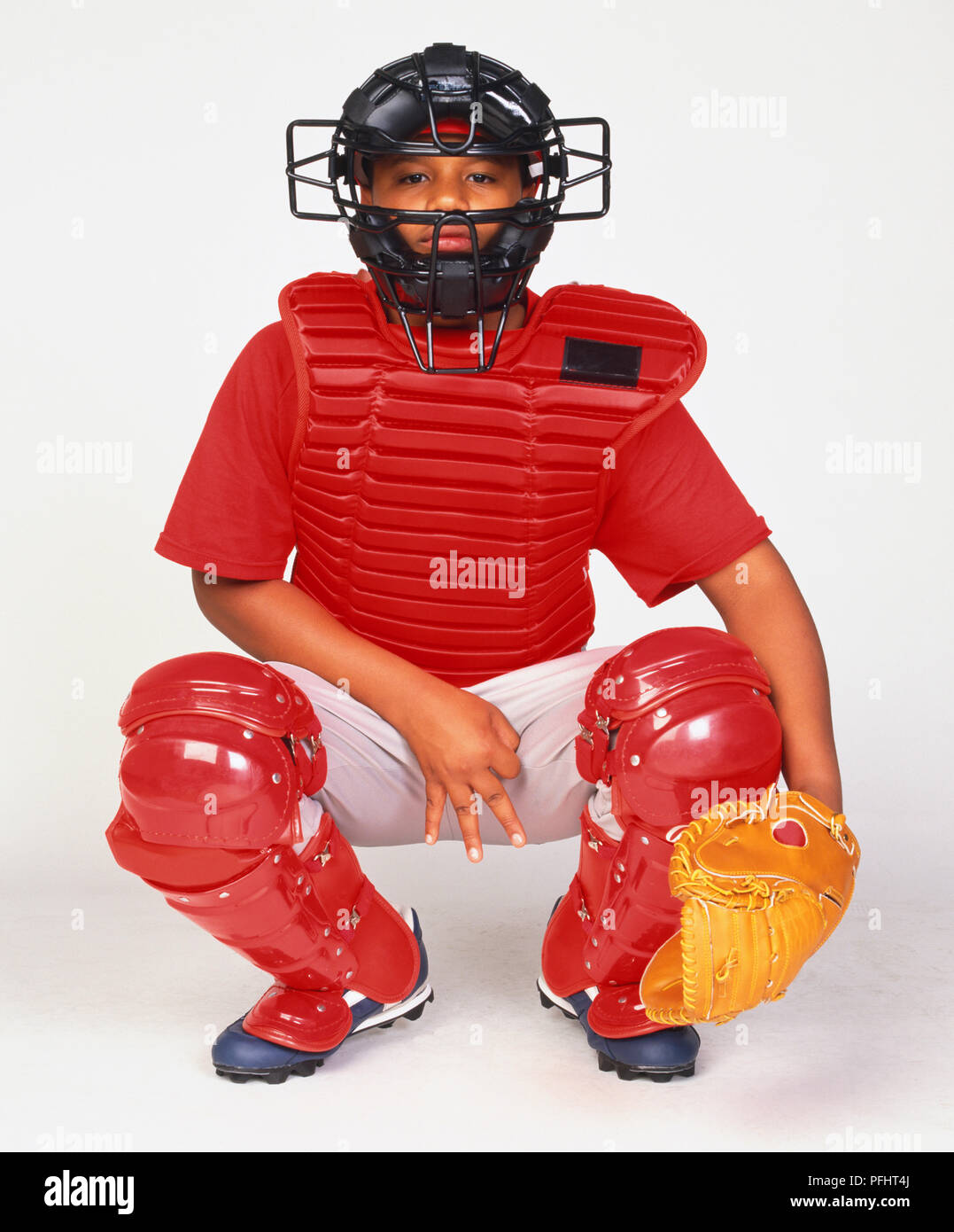 Junge in Baseball schützende Kleidung, Hockend, tragen, Maske, Brust Guard, feldspieler mit und leg Guards Stockfoto