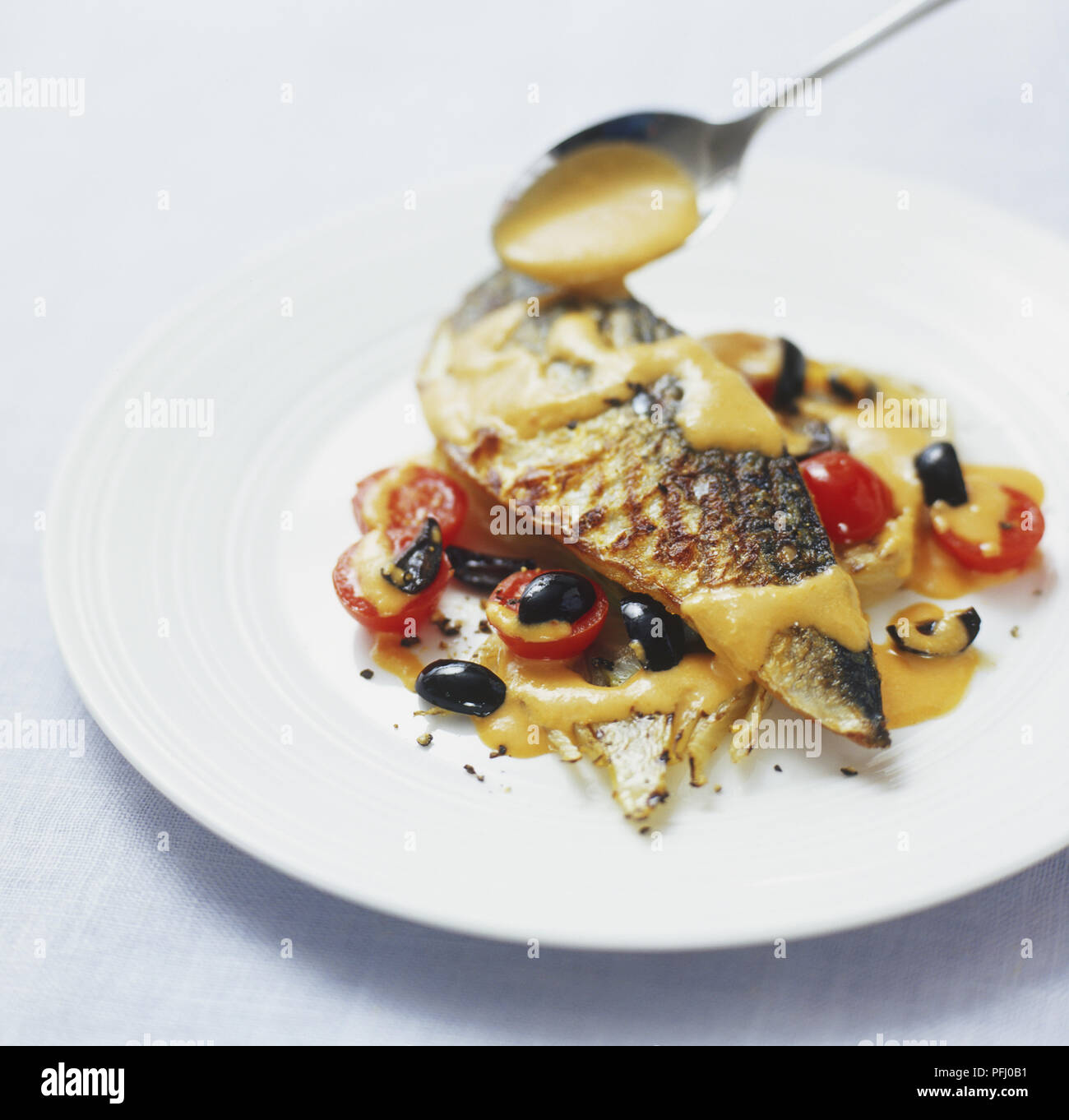 Romesco Soße über gegrillte Makrelen Filet mit schwarzen Oliven und Cocktailtomaten serviert Spooned Stockfoto