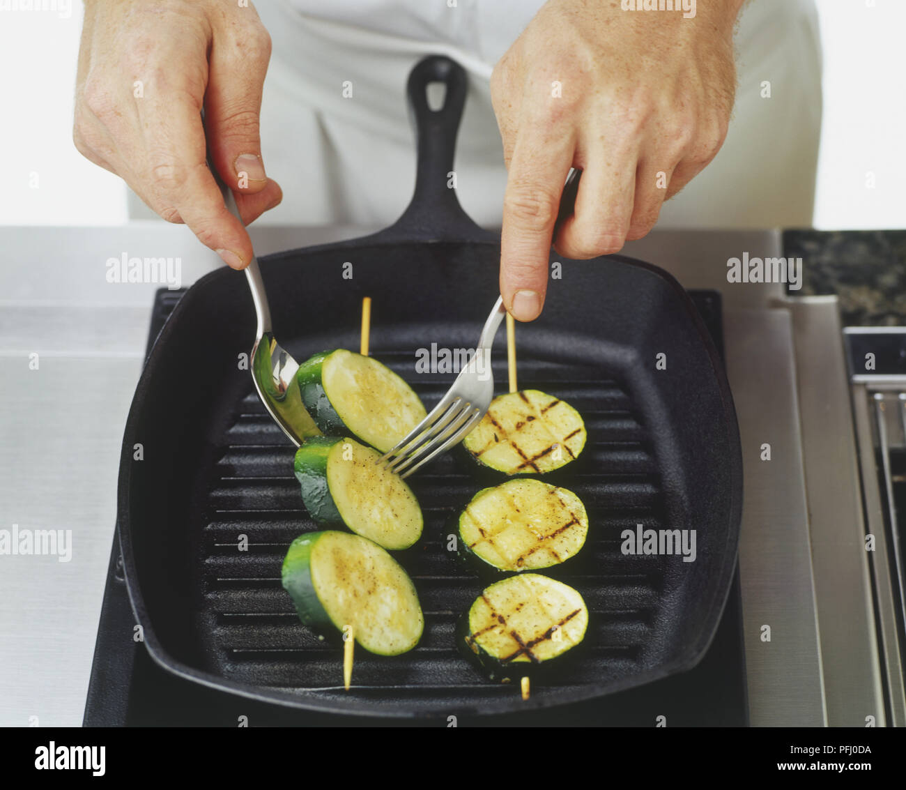 Zucchini spiesschen Kochen auf char-gril über gewendet mit Löffel und Gabel Stockfoto