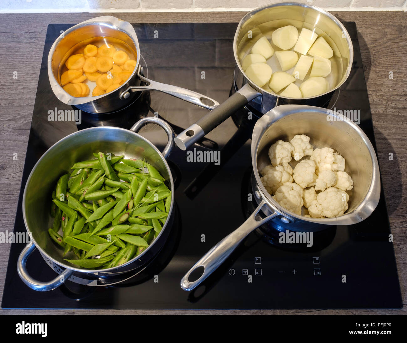 Vier Aluminium Töpfe mit frischem Gemüse auf Induktion Herd in der Küche  vor dem Kochen Stockfotografie - Alamy