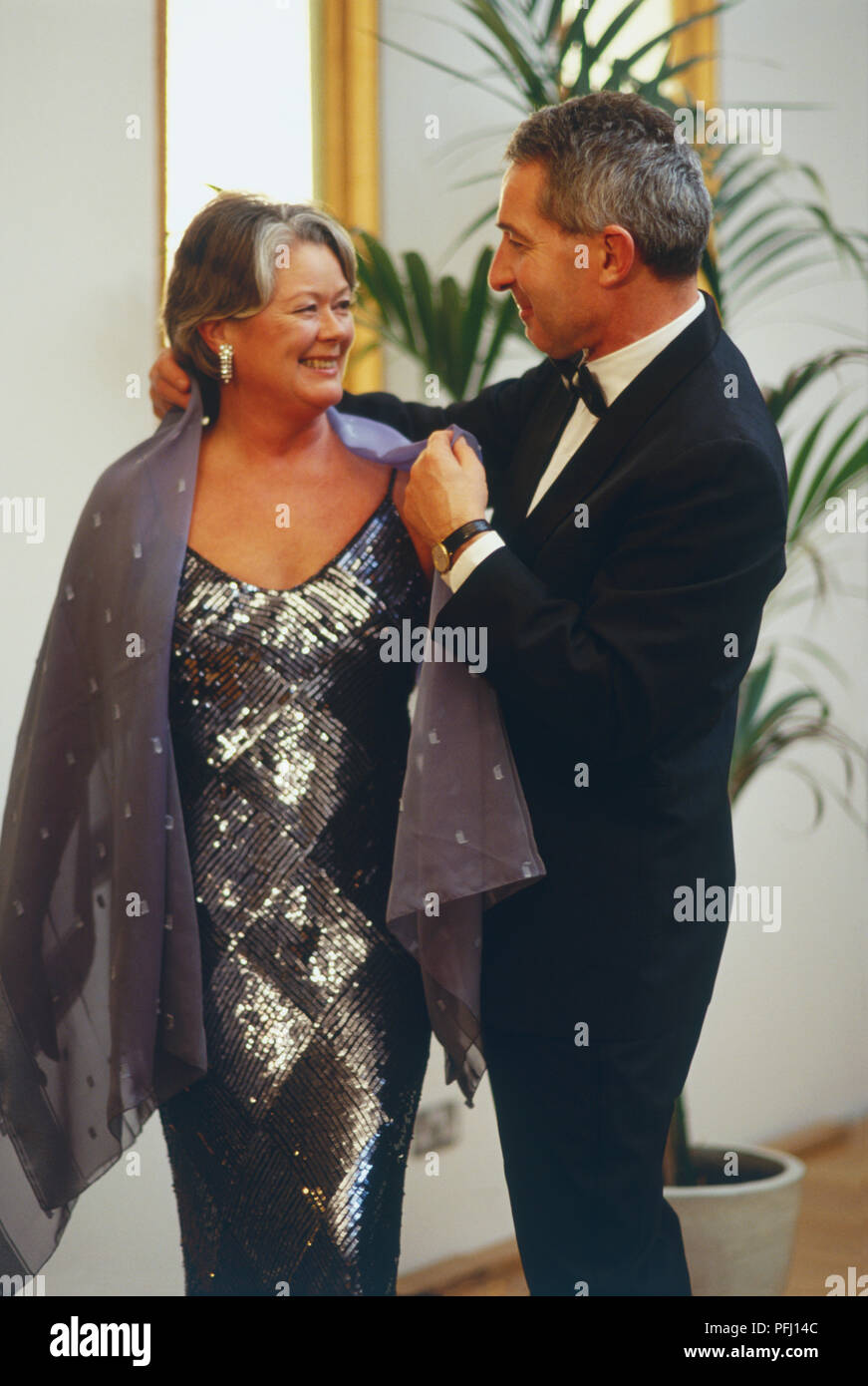 Reifer Mann helfen Frau mit ihrem Schal Stockfoto