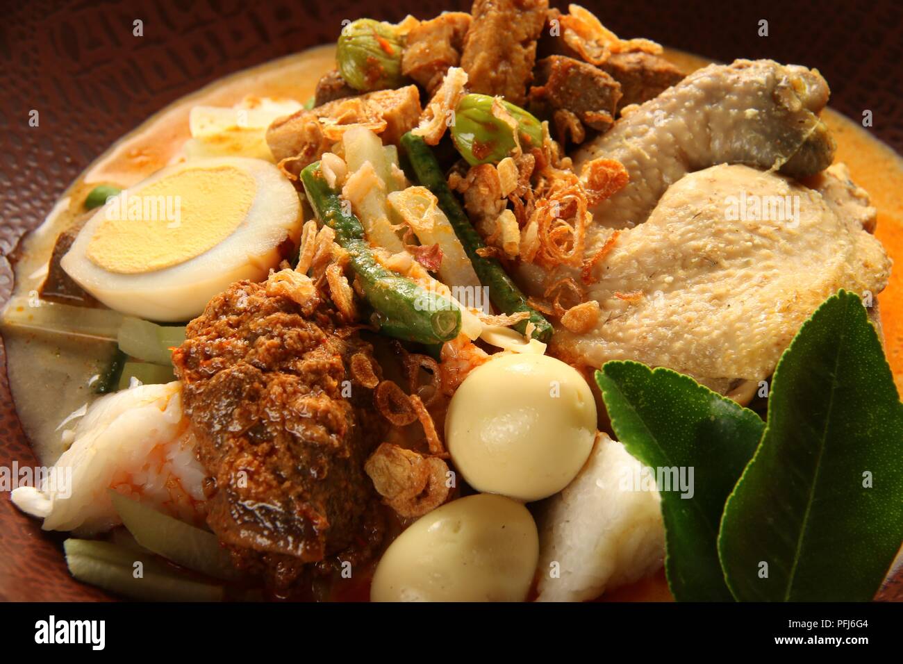 Ketupat Lebaran, die traditionelle feierliche Reisgericht mit Kuchen mit mehreren Beilagen; beliebt während Eid feiern. Stockfoto