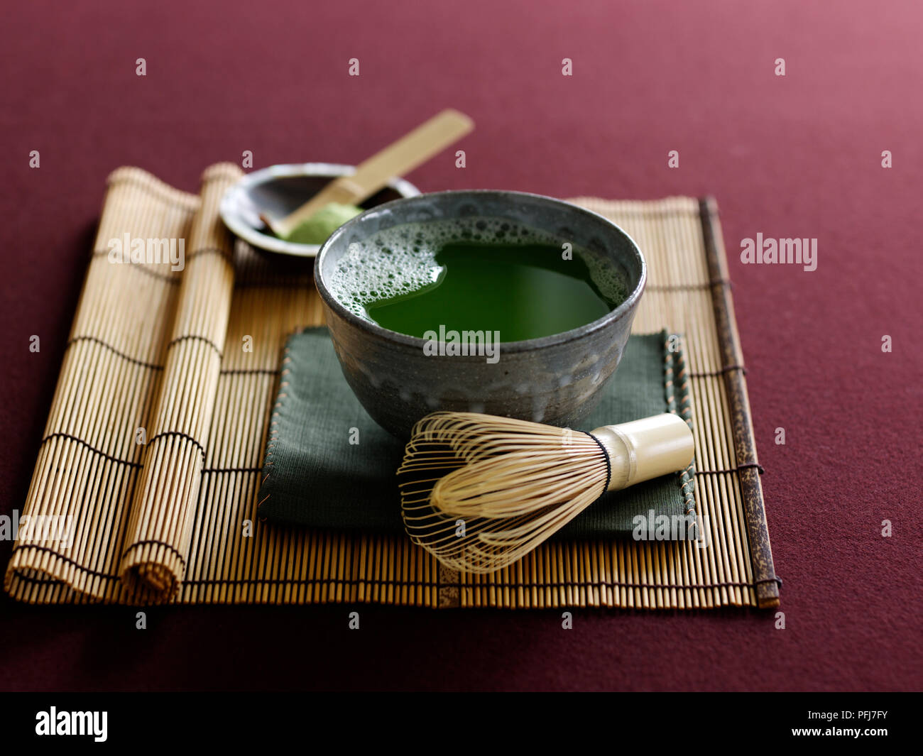 Schüssel grünem Tee, Strohmatte, Schneebesen, Geschirrspüler Stockfoto