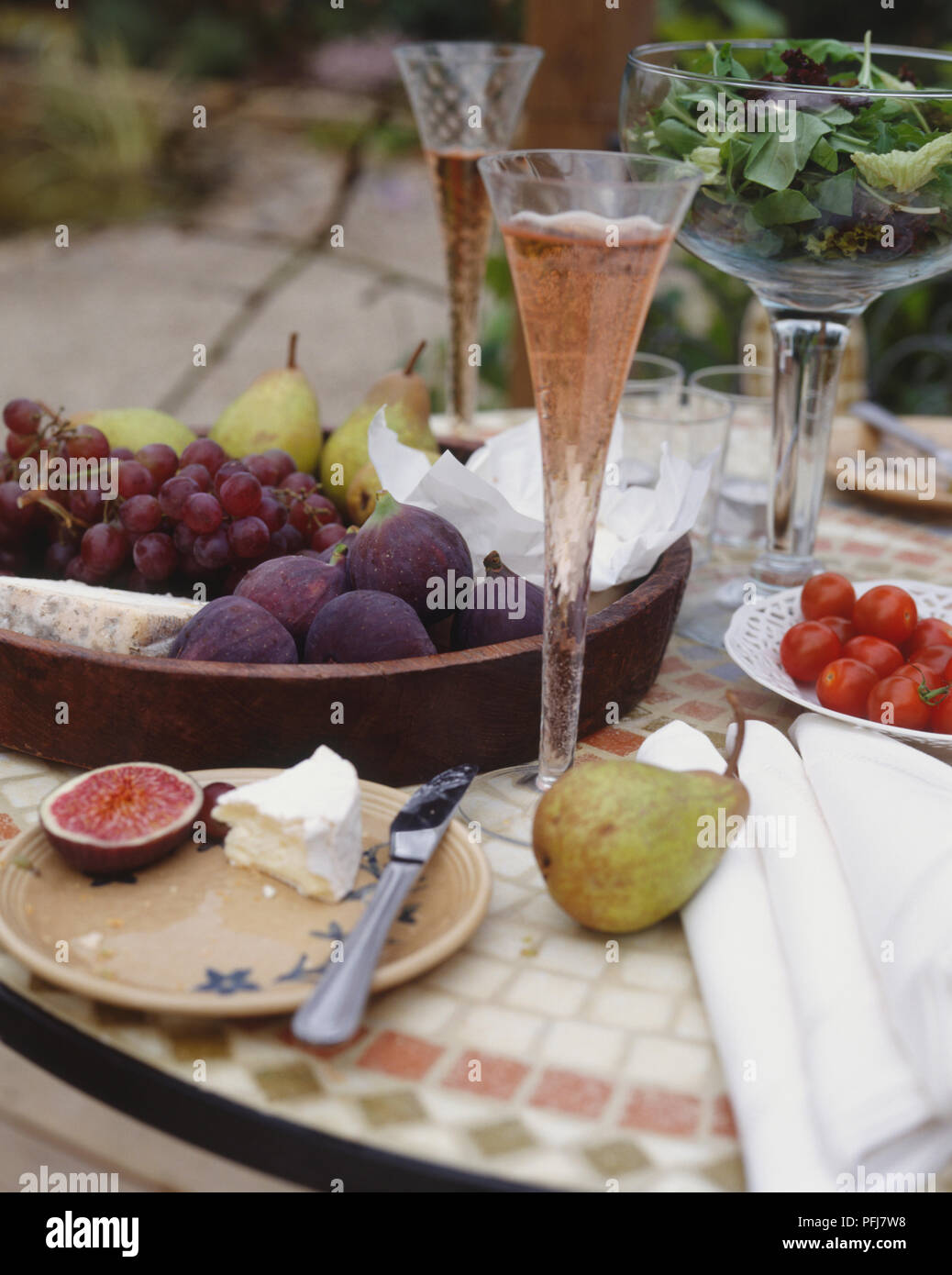 Reich verzierten Tisch mit Flöten der sprudelnden Flüssigkeit, und Schüssel von Feigen, Birnen, Trauben und Käse Stockfoto
