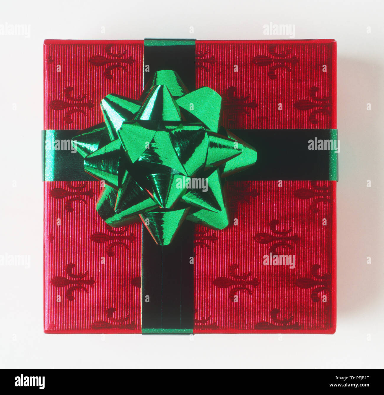 Geschenk verpackt in rot Fleur-de-lys Muster Papier und grünen Bogen Stockfoto