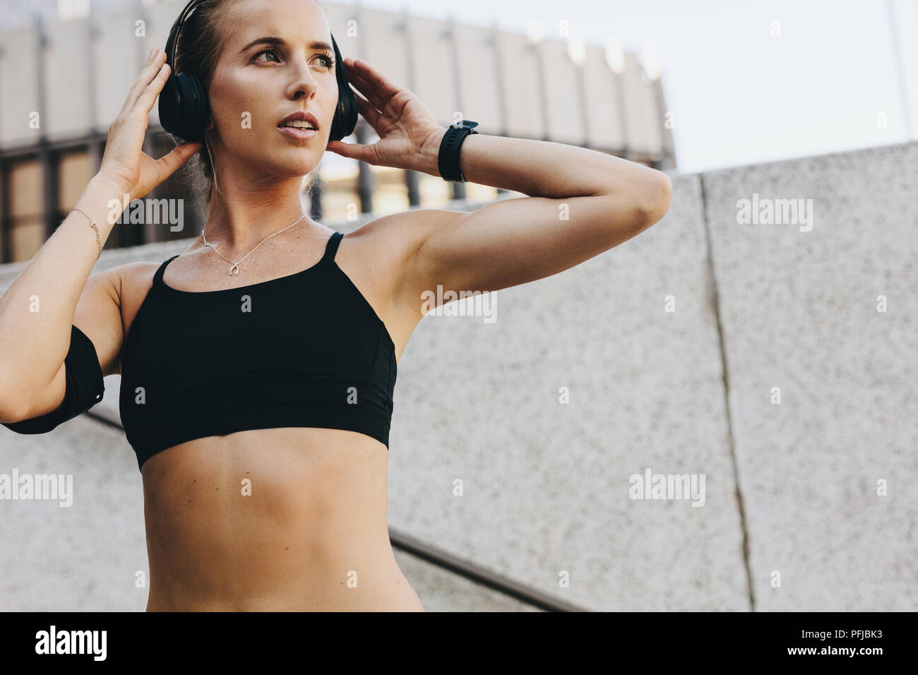Nahaufnahme eines Fitness Frau in Ausbildung Kleidung Musik auf kabellosen Kopfhörern. Frau Training im Freien Musik weg schauen Zuhören. Stockfoto