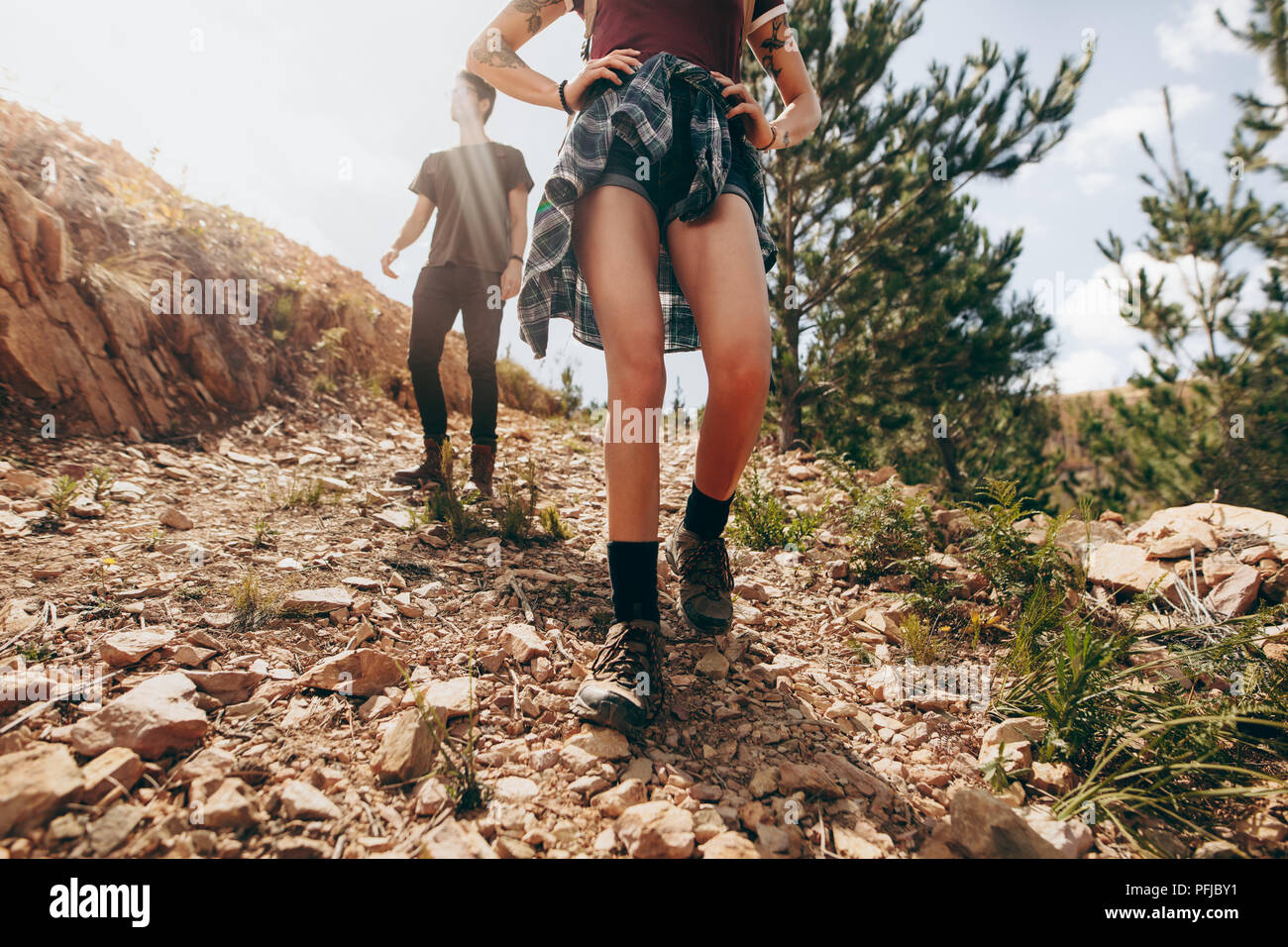 Explorer Paar in einem Wald. Frau gehen auf einem felsigen Weg mit Ihrem Partner nach Ihrem an einem sonnigen Tag. Stockfoto