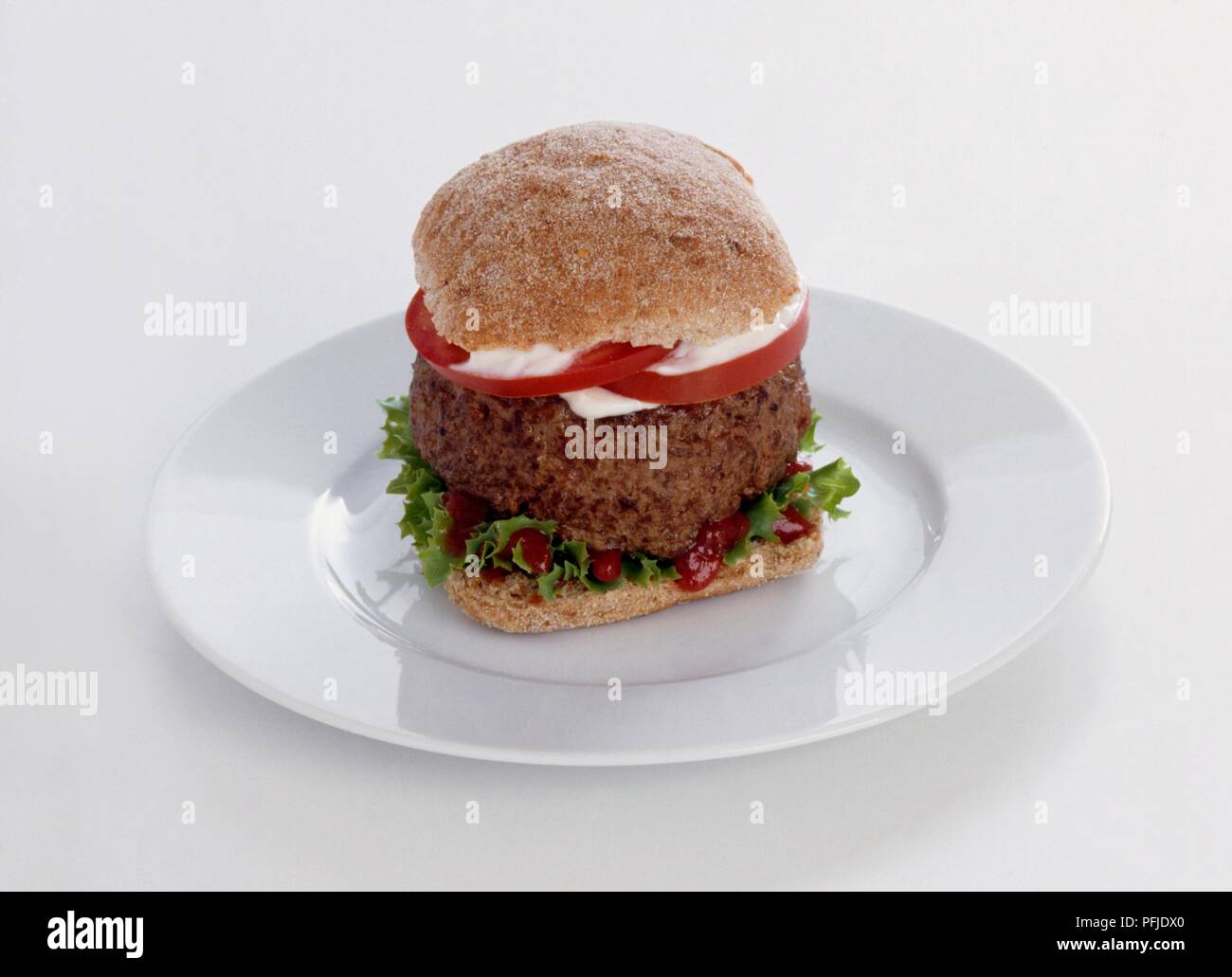 Burger in Vollkorn Brötchen mit Salat und Ketchup auf weiße Platte Stockfoto