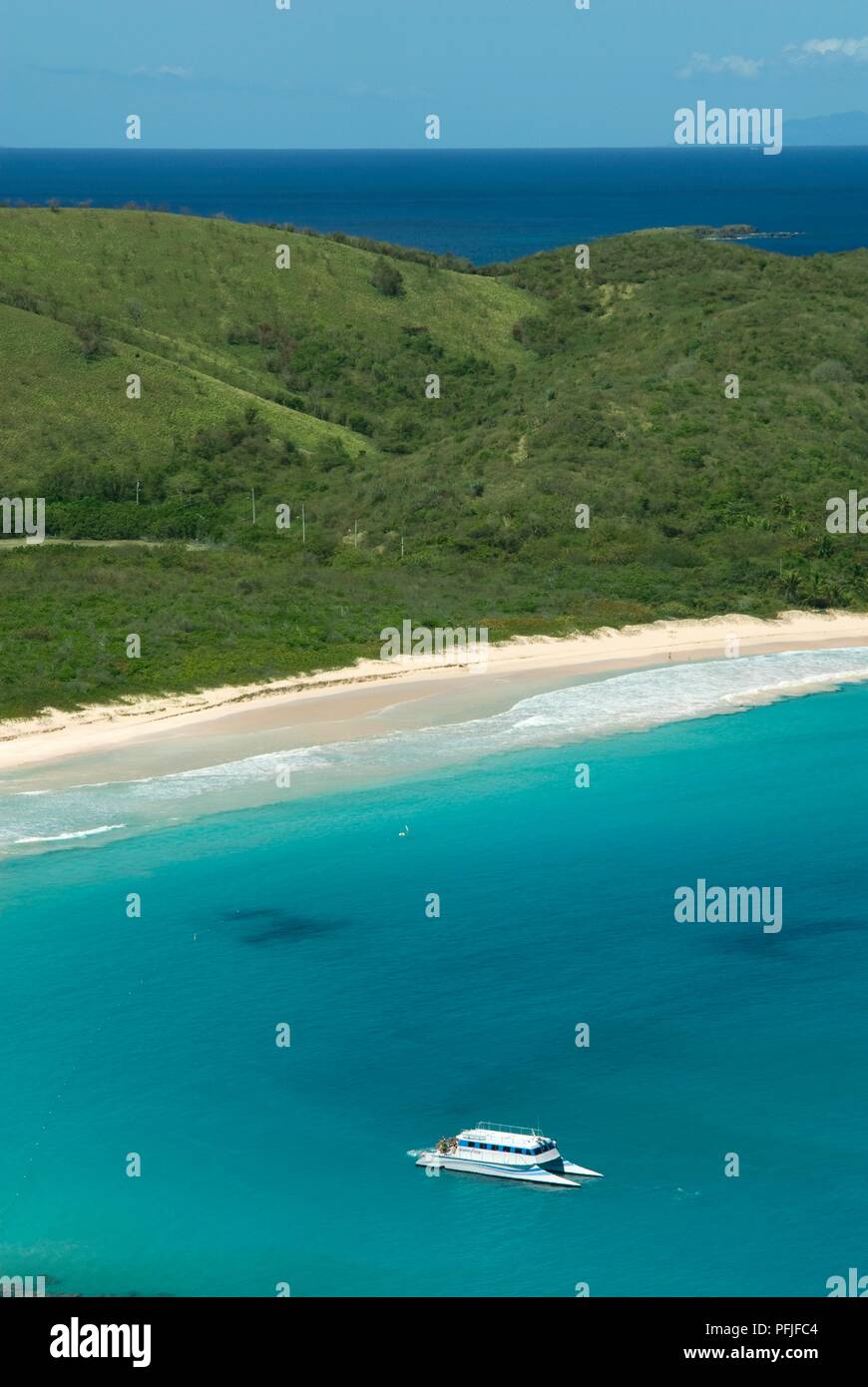 Puerto Rico Culebra Island, Playa Flamenco, Blick auf die grüne Küste, Strand und Katamaran im Meer Stockfoto