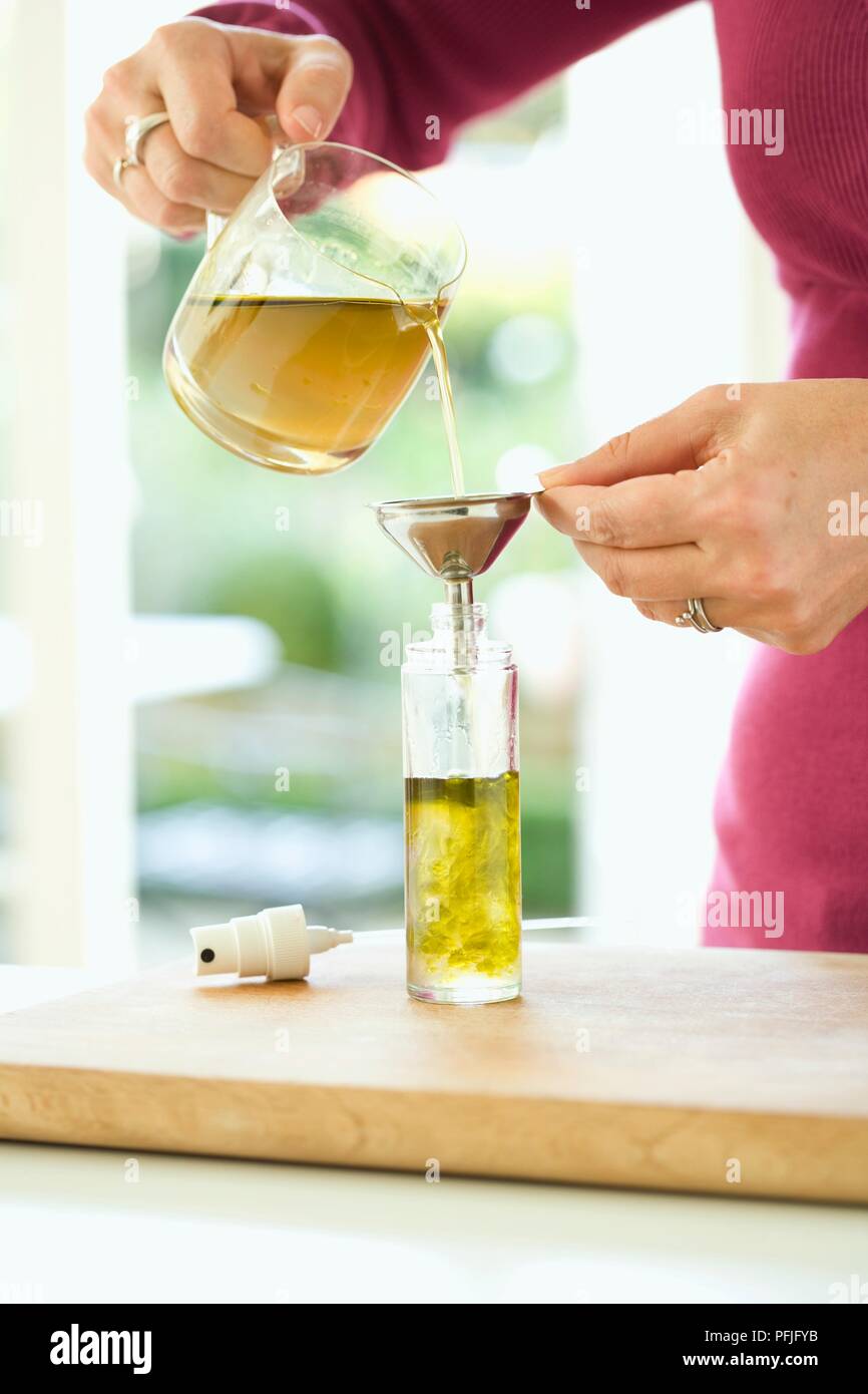Woman's Hand gießen Kamille Tee, Honig und Hanf Öl Mischung aus Kanne in Flasche mit Pumpspray oben (die natürliche baby Cleansing Lotion) Stockfoto