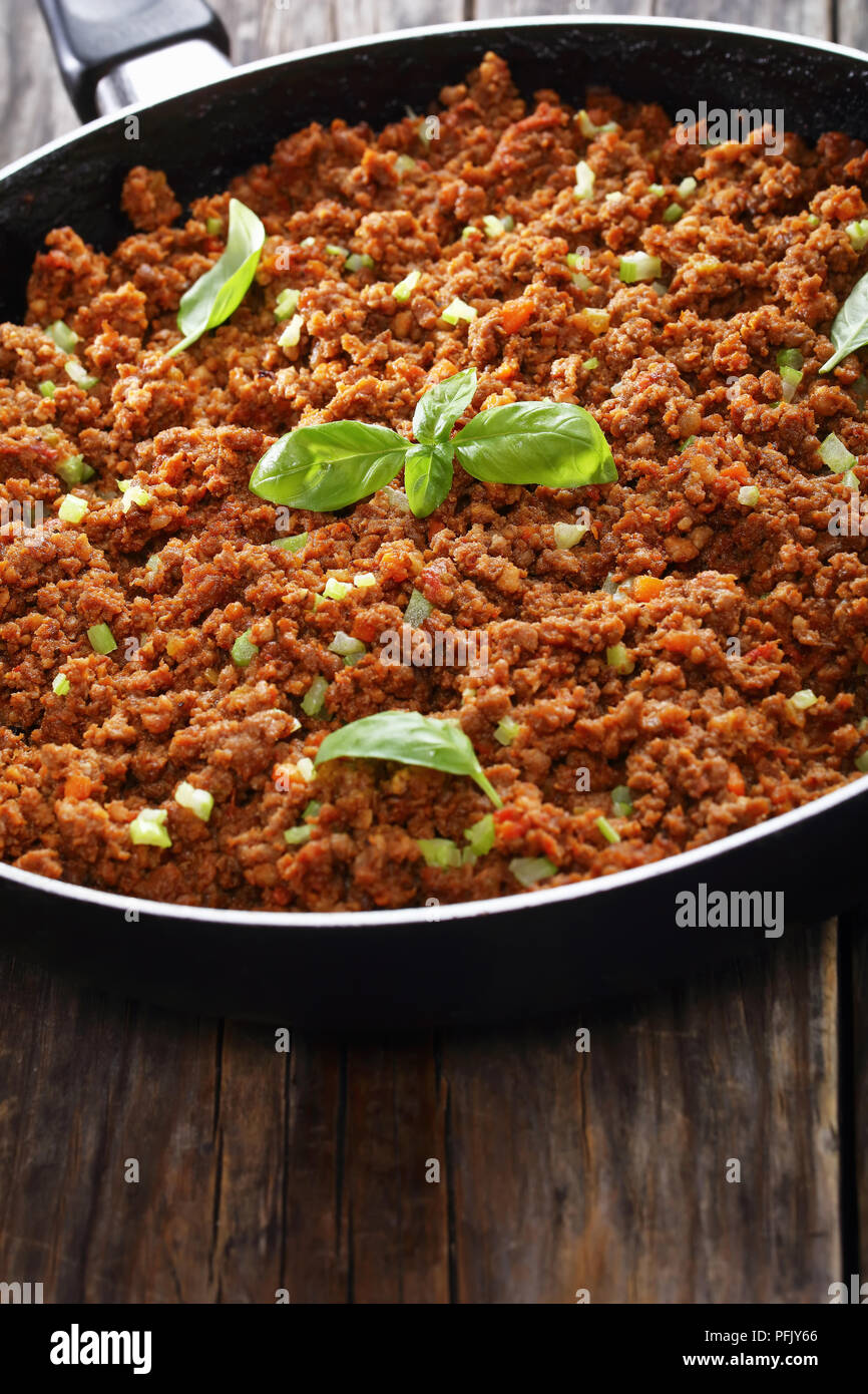 Leckere heiße Fleisch Ragout bolognese mit Tomatensauce, fein Gemüse und Kräuter in der Pfanne auf alten Holztisch gehackt, authentische Rezept, Ansicht von Stockfoto