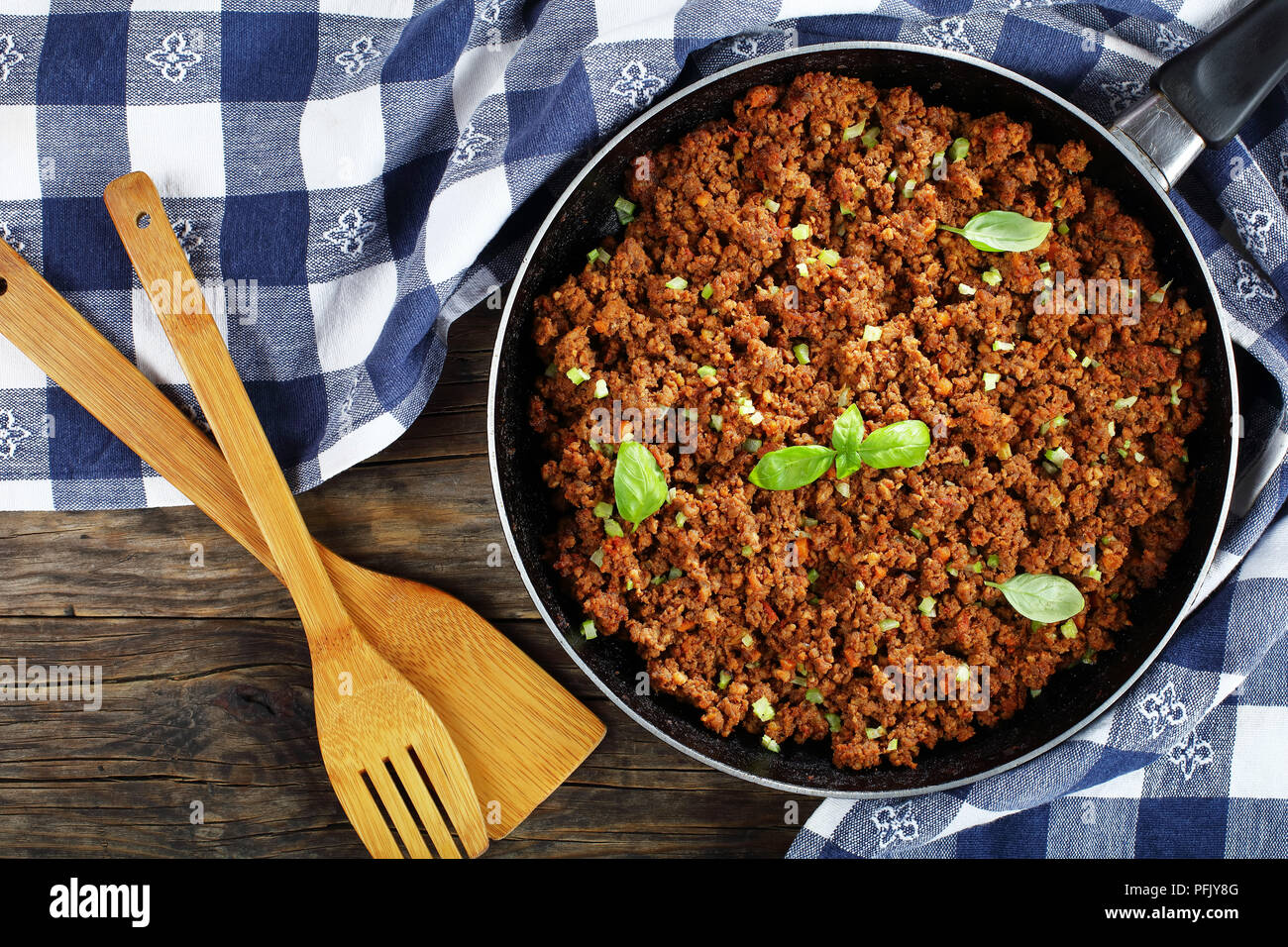 Bolognese Sauce - Hot Juicy Rinderhackfleisch geschmort mit Tomatensauce, Gewürze, Basilikum, fein gehackt Gemüse und Sellerie in Skillet auf Holztisch mit Stockfoto