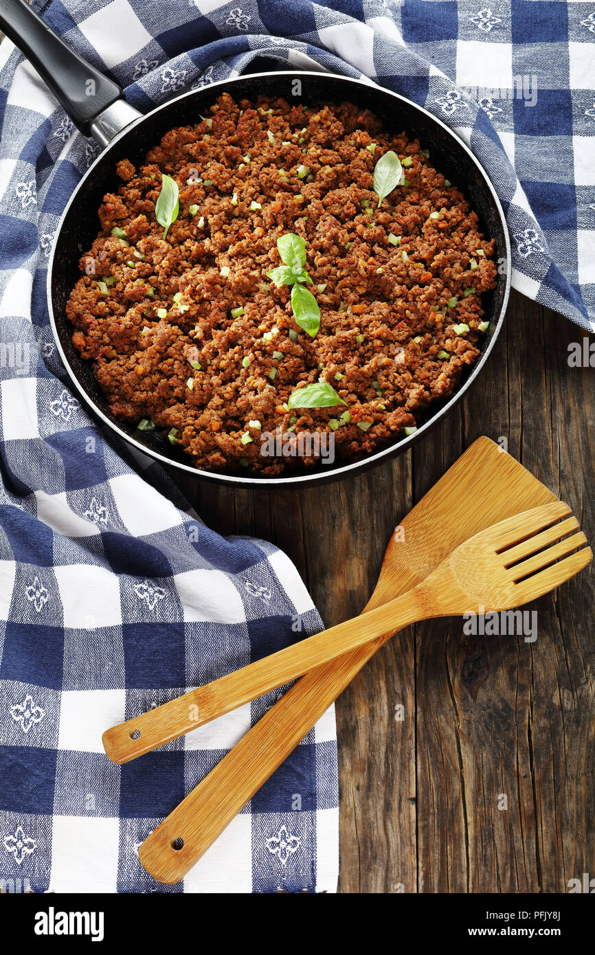 Leckere bolognese Ragout - Hauptbestandteil für Pasta oder Lasagne in der Pfanne auf Holztisch, vertikale Ansicht von oben Stockfoto