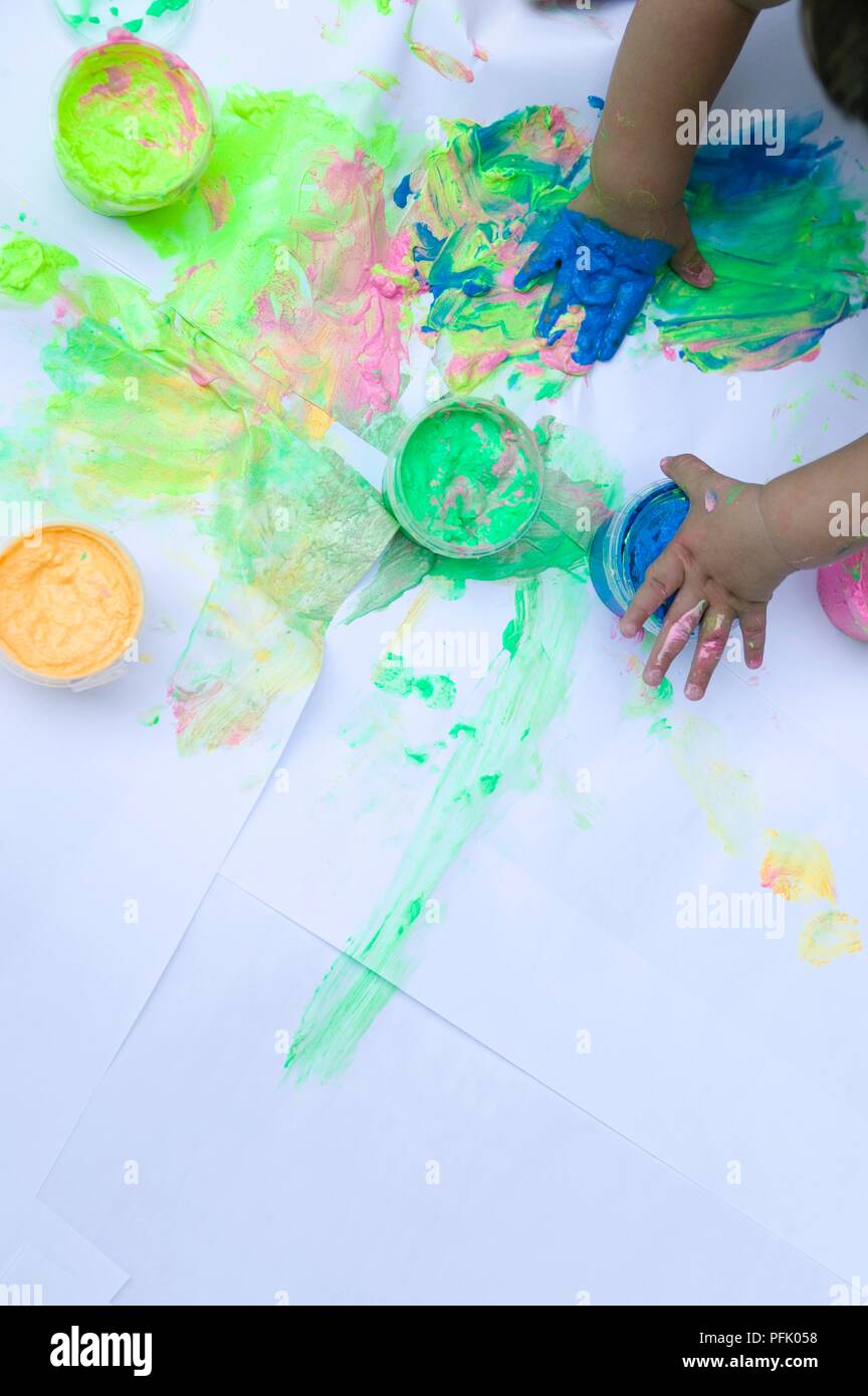 Der Toddler Hände mit Farbe verschmiert, Blatt Papier und Töpfe von Farbe, über dem Boden Stockfoto