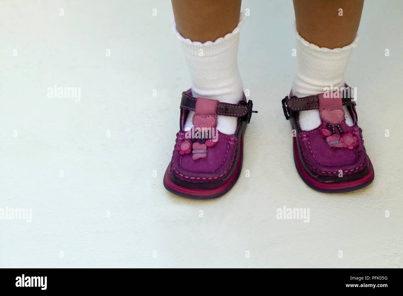 Toddler mit Paar lila Schuhe auf dem falschen Fuß, close-up Stockfoto