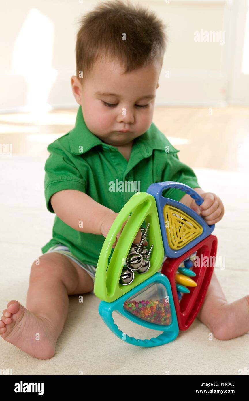 Baby Junge sitzt auf dem Boden spielen mit der rassel Spielzeug, close-up Stockfoto