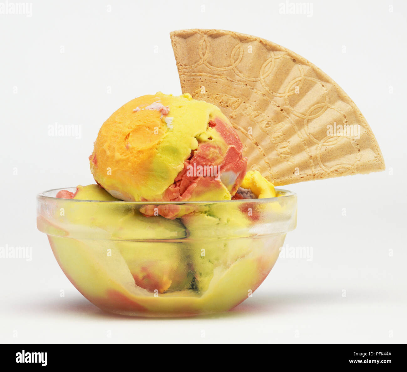 Mehrfarbige, Fruchtsaft- und aromatisierte Getränke ohne Eis dekoriert mit einem Wafer, in einer Glasschale Stockfoto