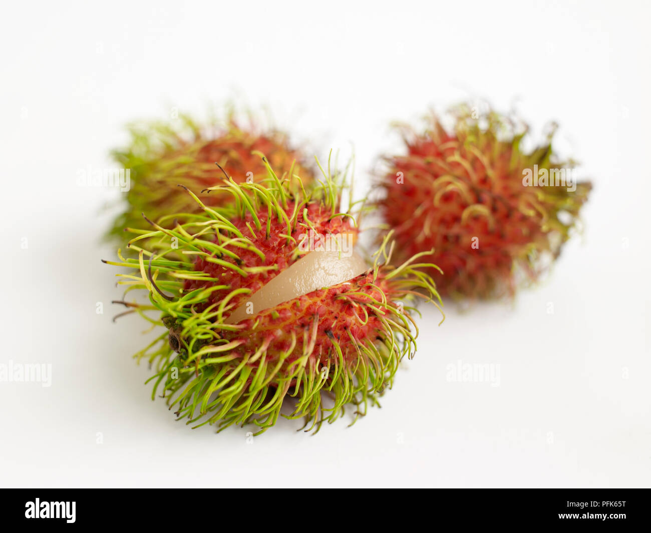 Drei Rambutan, einer teilweise Öffnen, Schließen Stockfoto