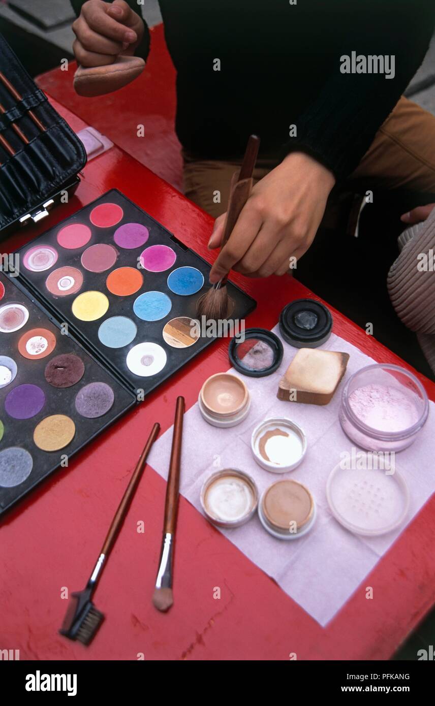 China, Zhenjiang, Shaoxing, Yue Opera, Hand, die Make-up-Pinsel über bunte Make-up Palette Stockfoto