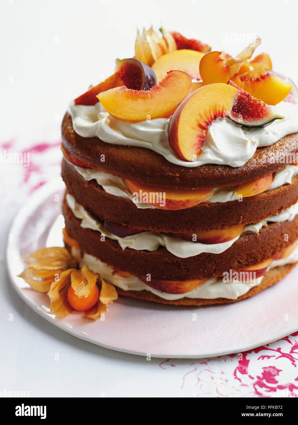 Frisches Obst und Sahne Torte mit Pfirsichen und Feigen, auf Teller serviert, garniert mit einem kumquat Stockfoto