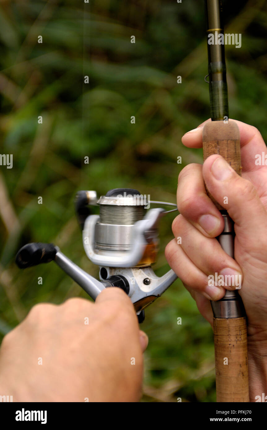 Des Menschen Hände halten Angelrute mit festen Steuerschieber für Haspeldrehzahl für Süßwasser Angeln, close-up Stockfoto