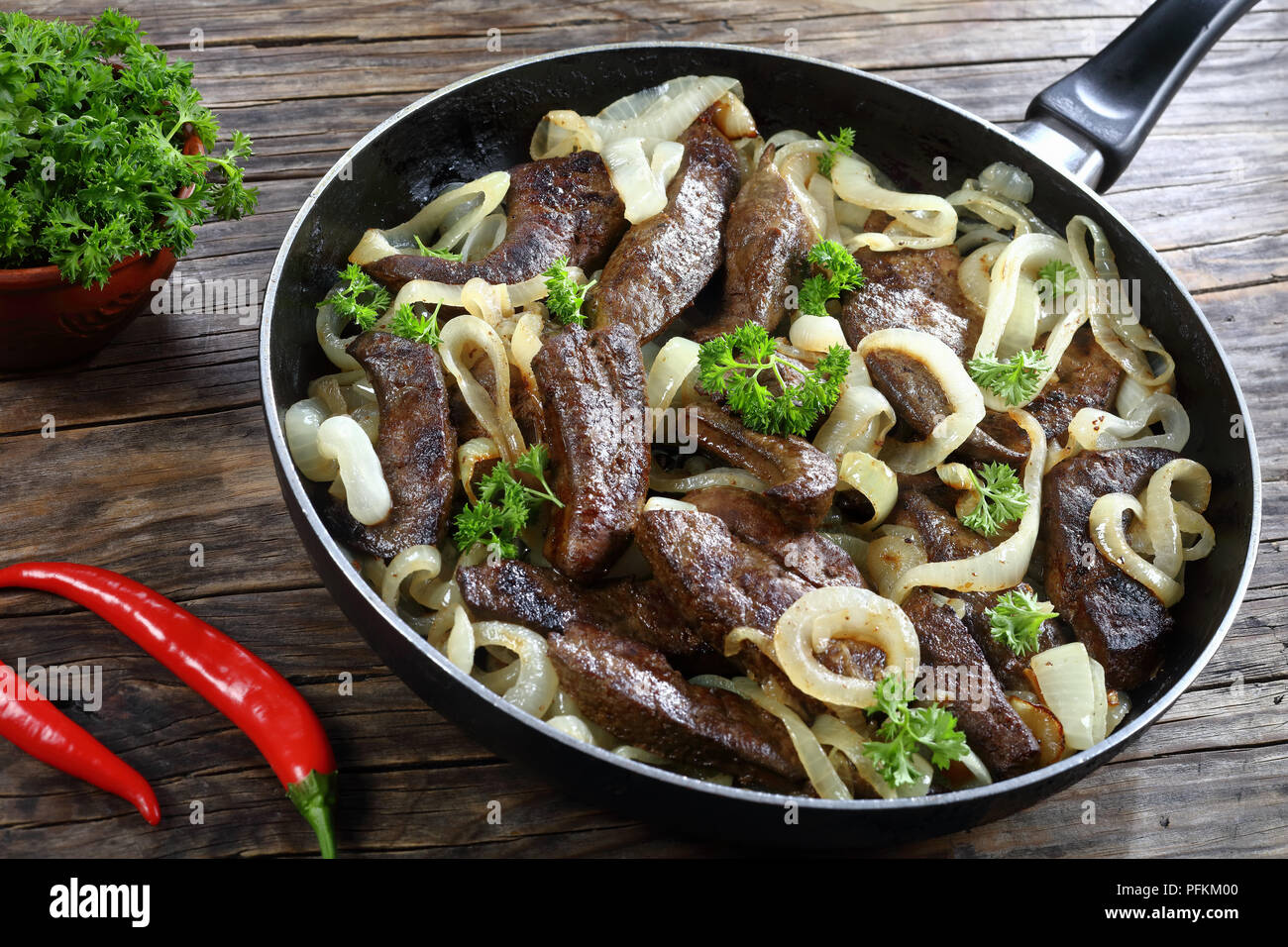 In der Nähe von köstlichen gut gekochte Kalbsleber Stück gebraten mit Schalotten Ringe in Pfanne, Ansicht von oben Stockfoto