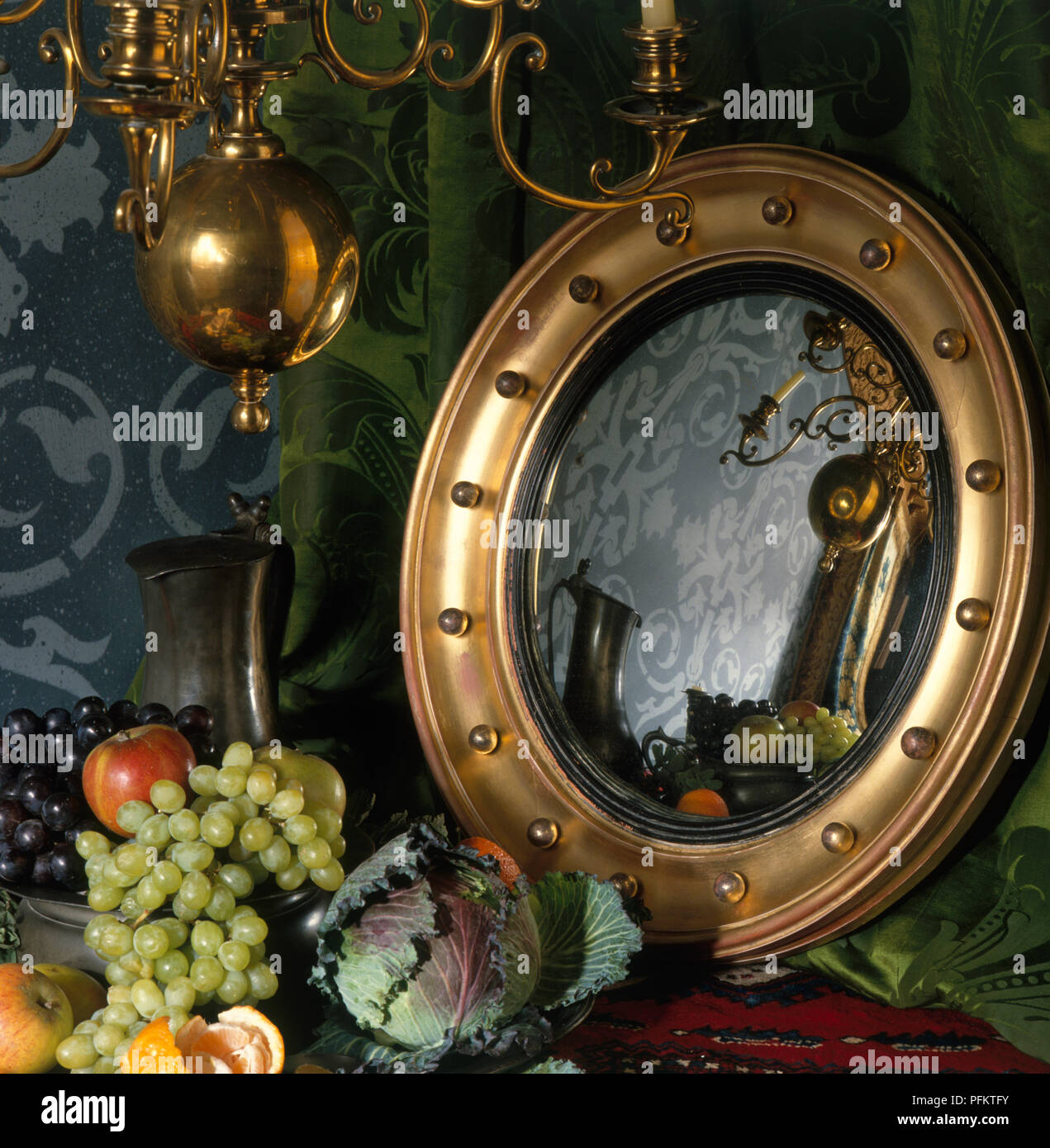 Konvexe gold reflektierenden Spiegel messing Kronleuchter und Obst Anordnung Stockfoto