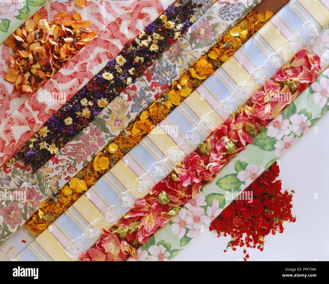 Eine Vielzahl von Stoffen in Brötchen mit getrockneten Blumen angezeigt in zwischen jedem Stoff. Stockfoto