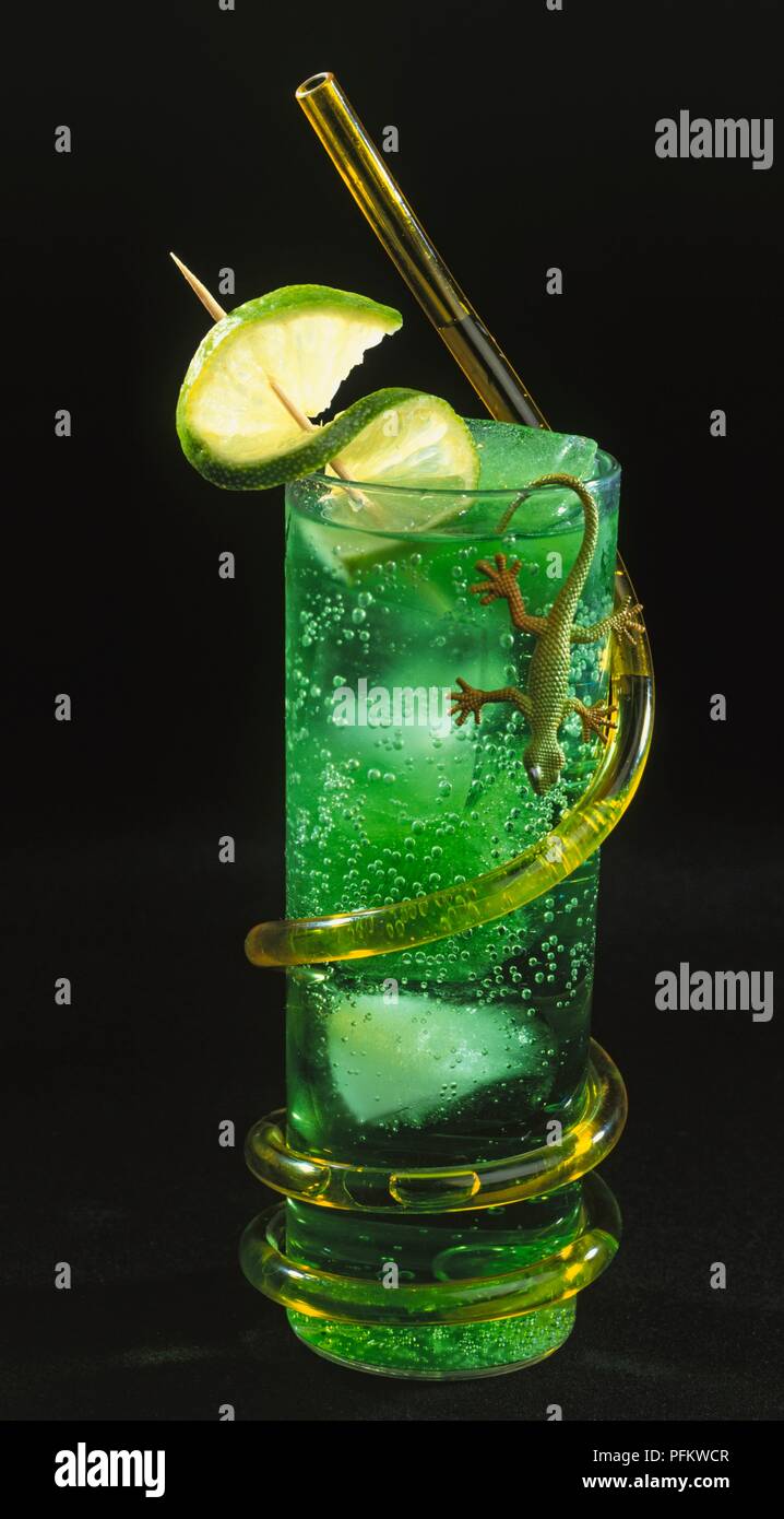 Grüner cocktail garniert mit Kalk, mit einem Kunststoff Lizard und Strohhalm um auf der Außenseite gewickelt eingerichtet Stockfoto