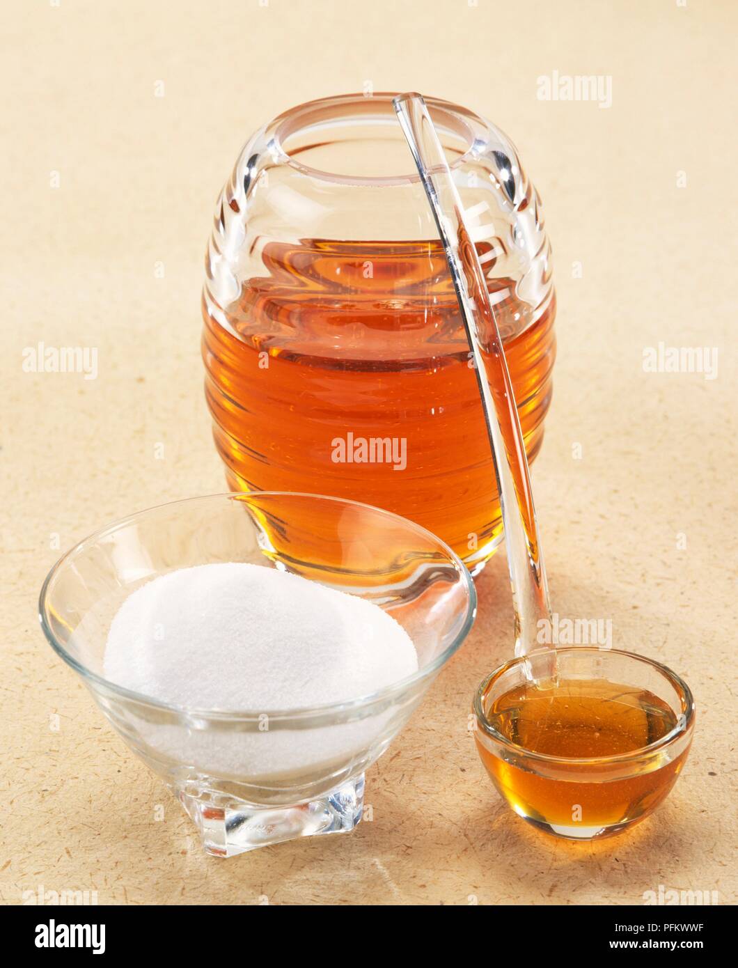 Honig im Glas und in der kleinen Schüssel mit Löffel und Schüssel von Weißzucker Stockfoto