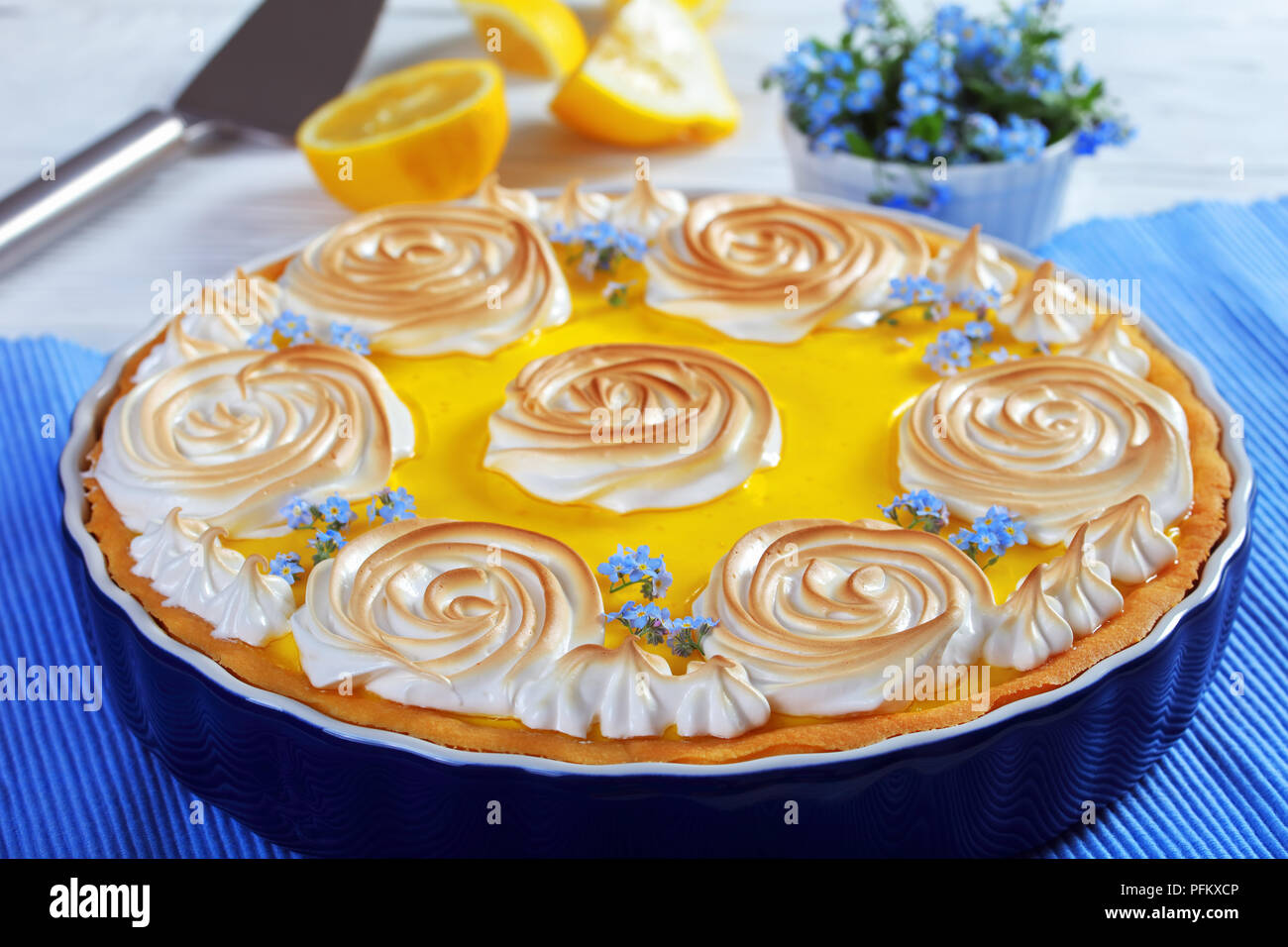 Klassische französische Lemon tart - frische Backwaren mit einer glatten Zitrone Füllung mit Baiser Rosen und genießbaren frischen Blumen, Ansicht von oben, close-up Stockfoto